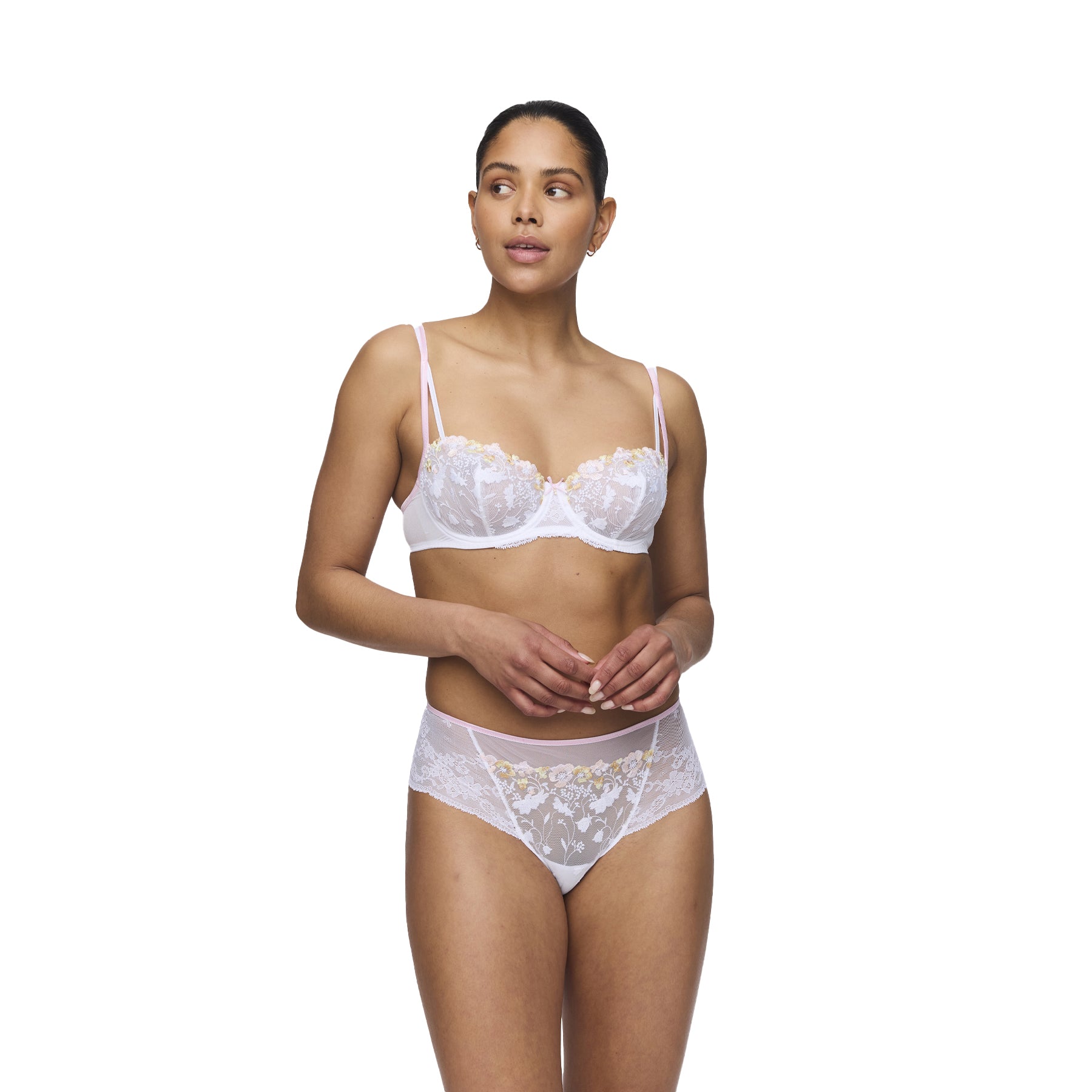 A model wears a white lace balconette bra with floral embroidery and matching high-waisted lace briefs, posing elegantly against a plain white background.