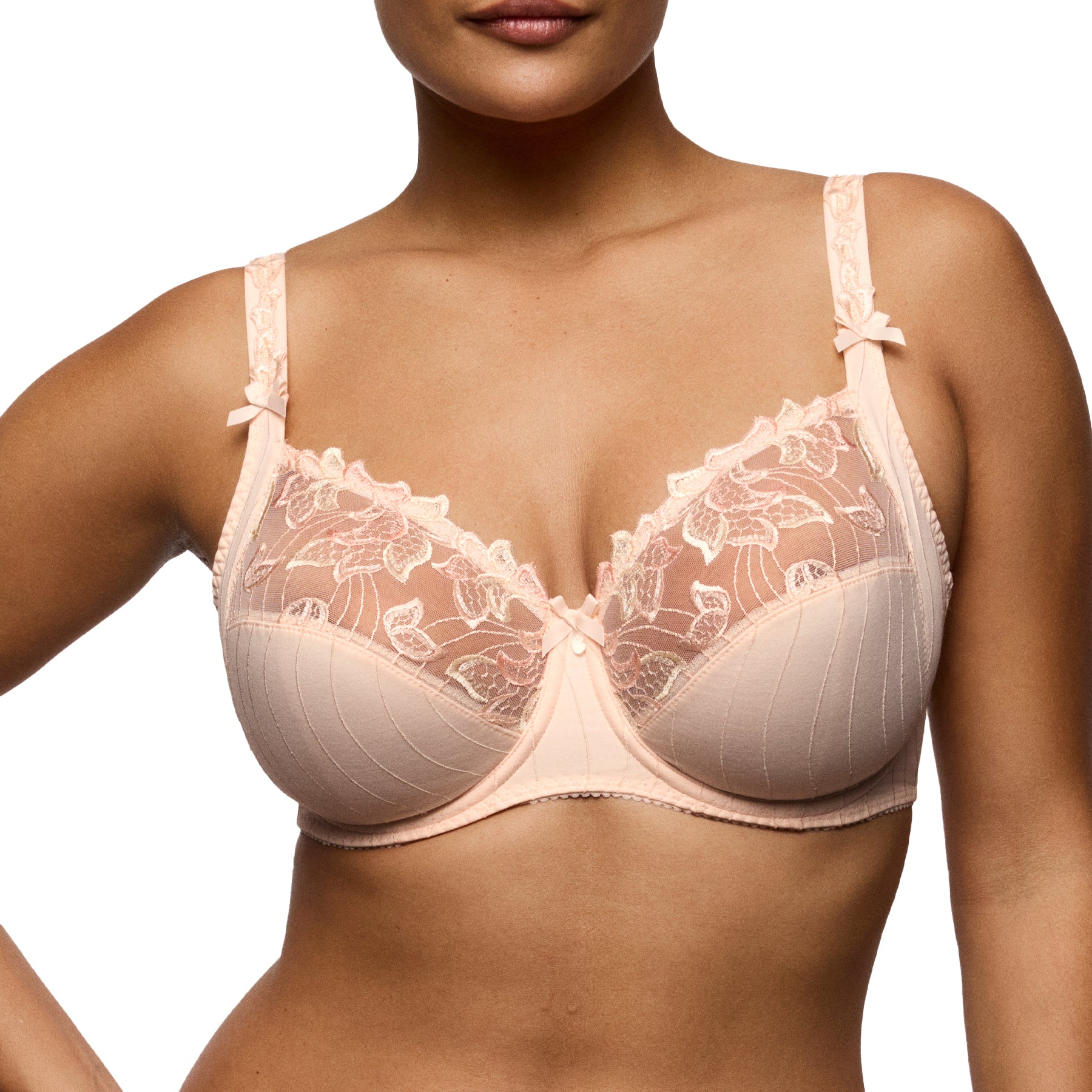 Front view of a blush embroidered underwire bra on a model, emphasizing the natural shape, supportive structure, and refined lace finish.