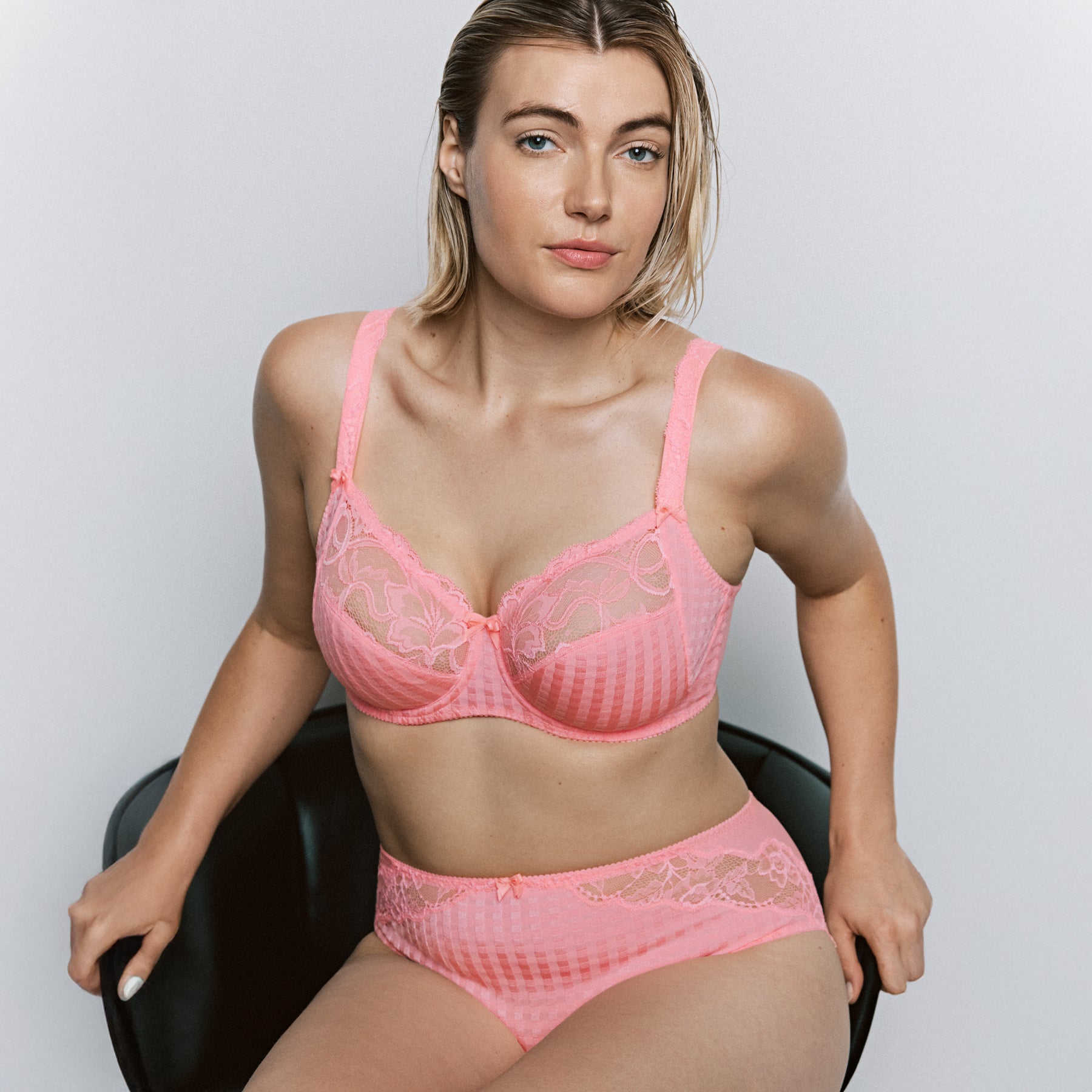 Woman wearing pink lace underwire bra and matching brief with floral lace cups and check pattern