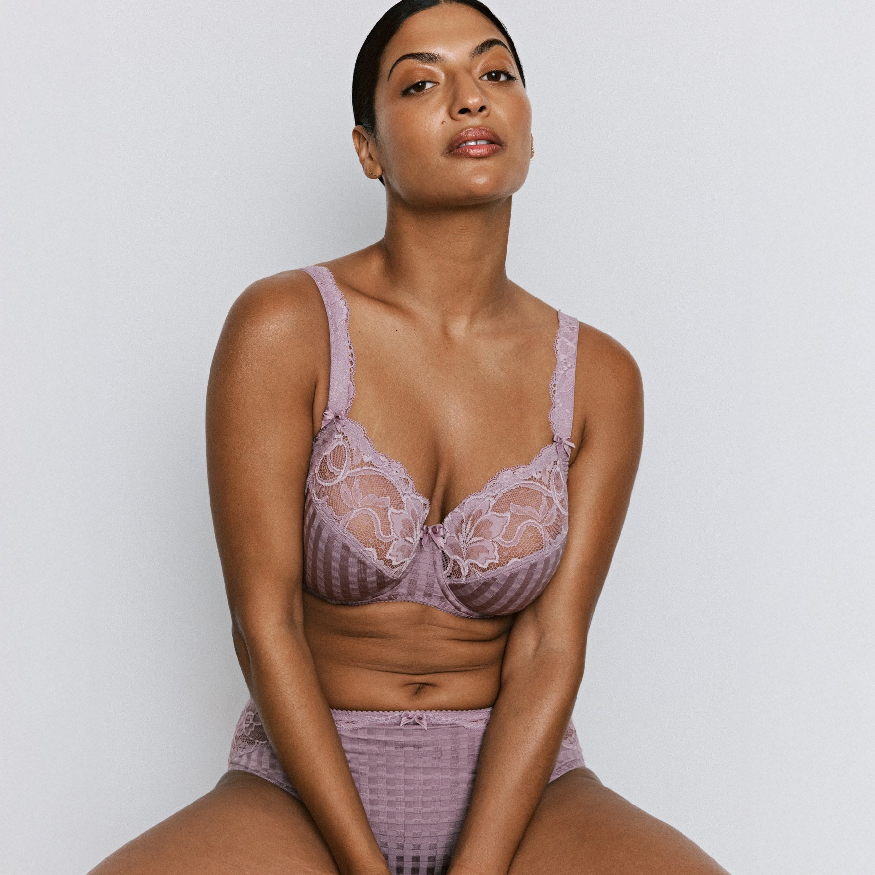 Front view of a mauve lace underwire bra worn by a model, featuring floral lace cups and supportive structure.
