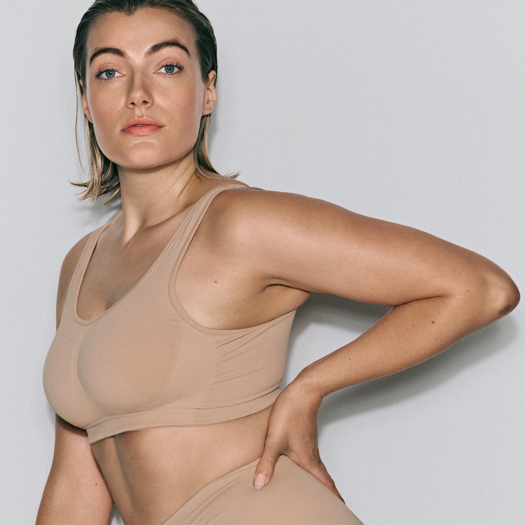 Close-up front view of seamless nude scoop-neck wireless bra with wide straps and smooth finish