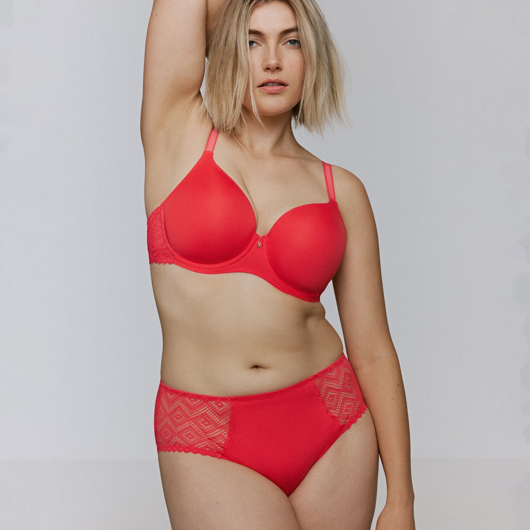 Full-body view of model wearing a coral full-coverage bra with matching high-waist brief, showing smooth cups and lace side panels.
