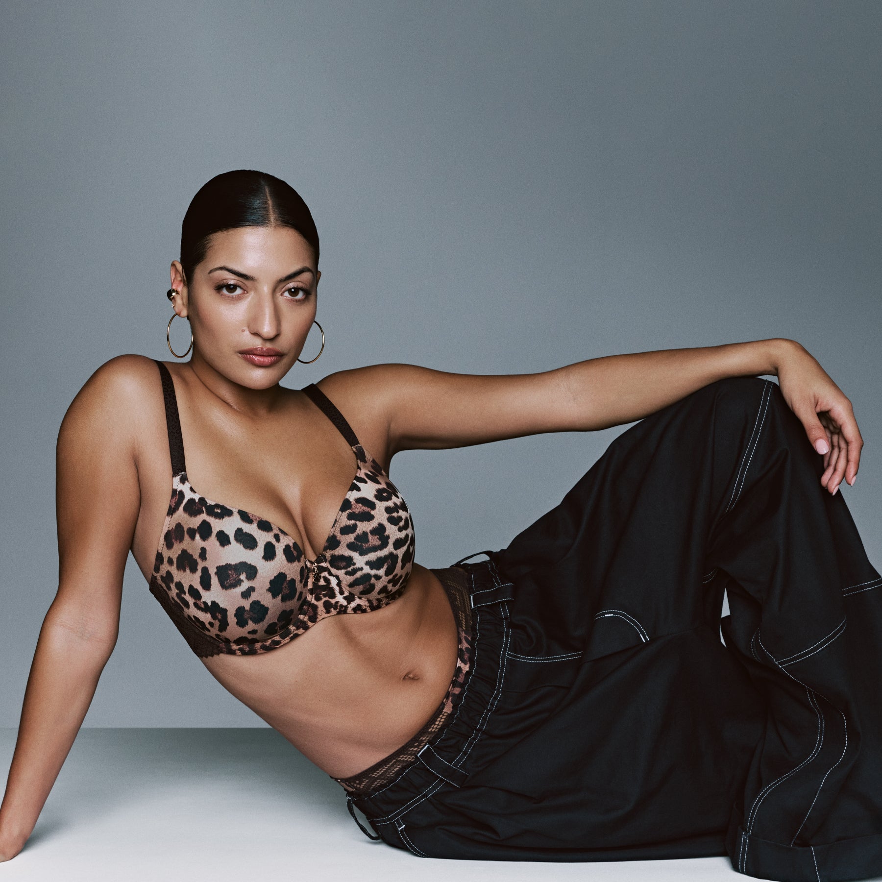 Model wearing a leopard print bra and matching brief styled with loose black trousers.