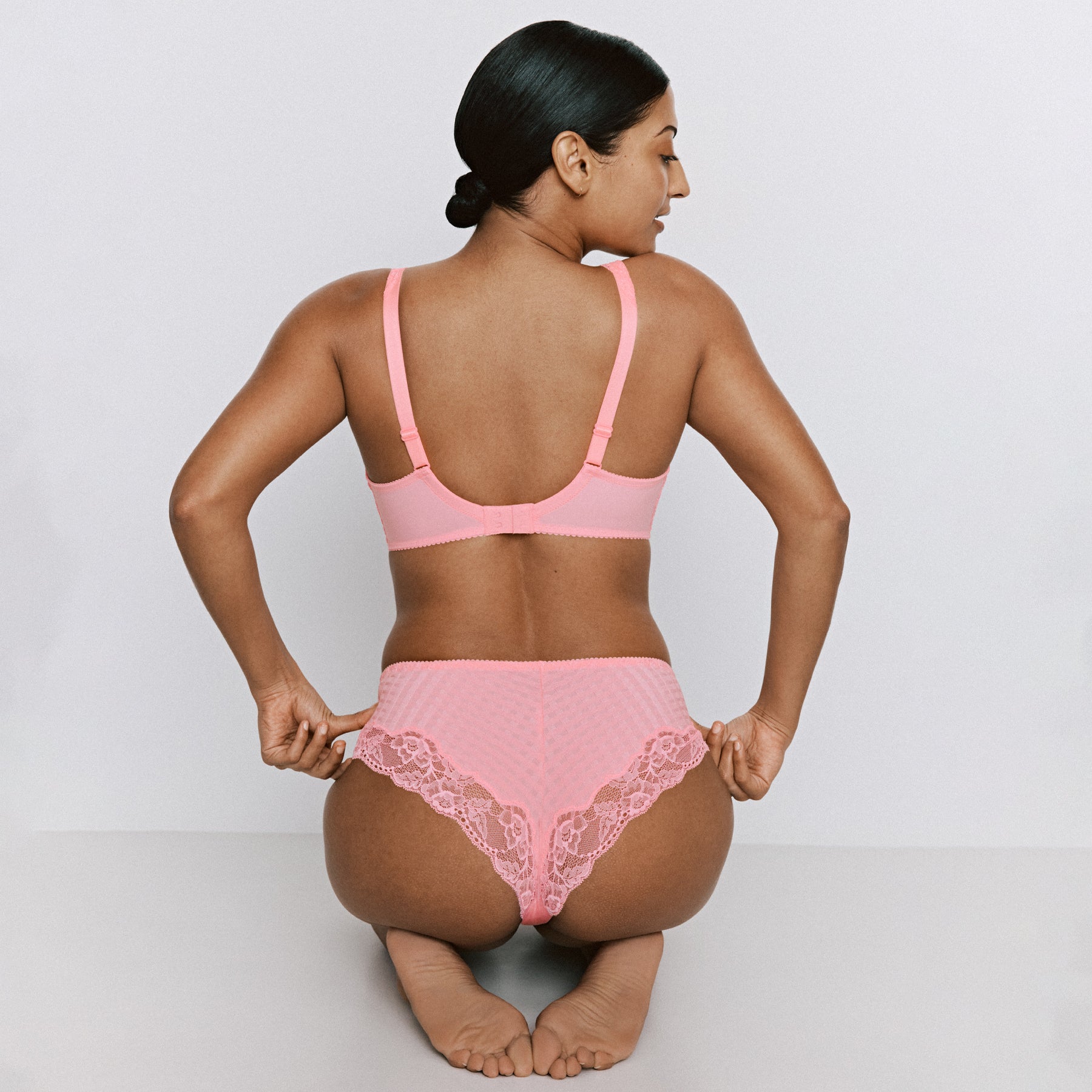 Woman wearing a pink bikini sitting on a white background
