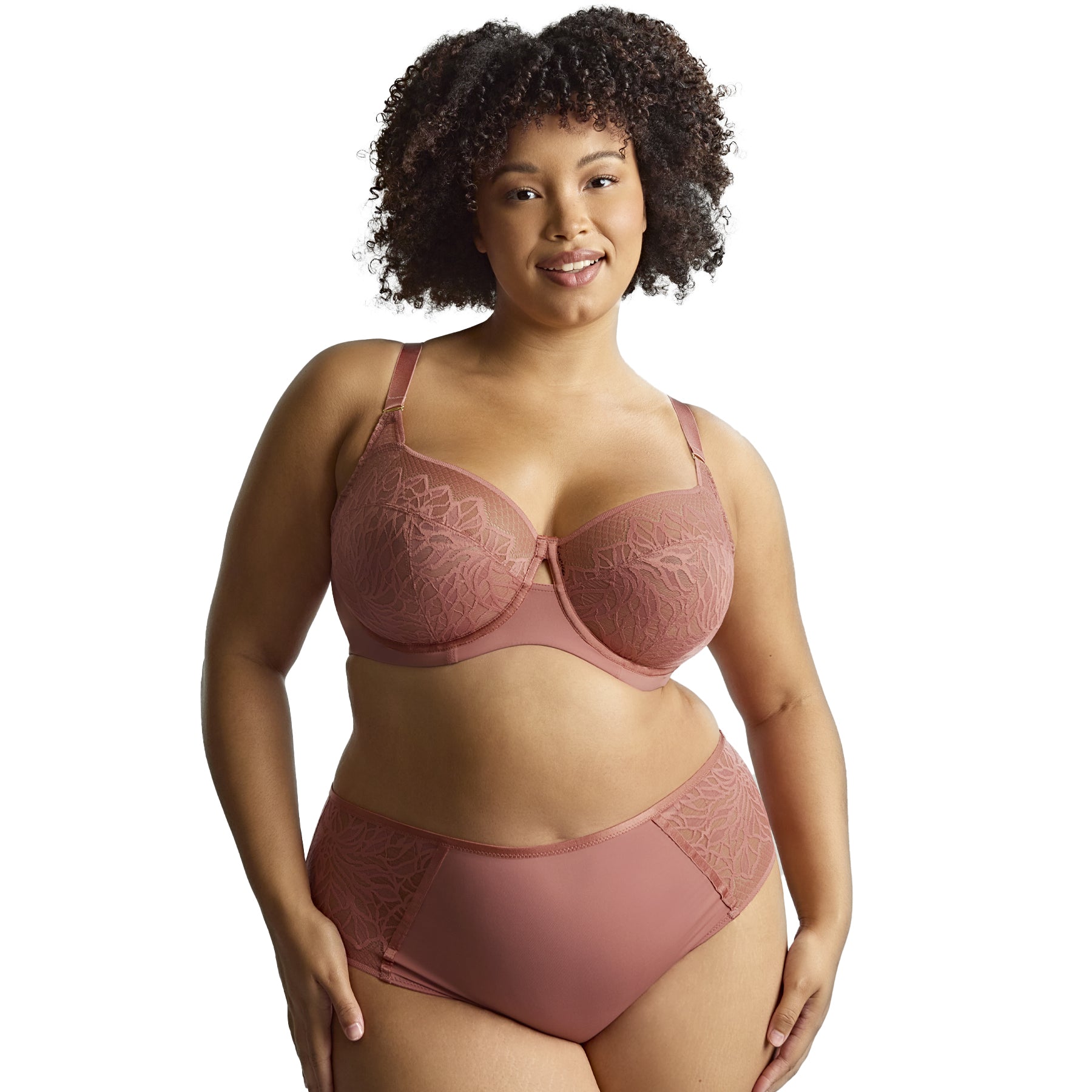 Plus-size model in sienna rose lace bra and full brief, posing confidently against white background.