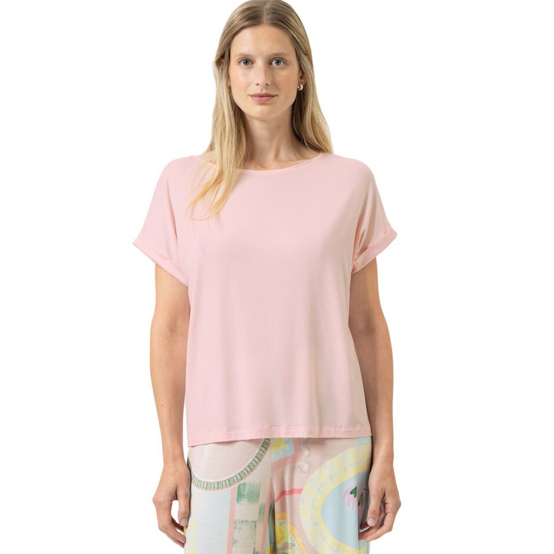 Woman wearing a soft pink short-sleeve T-shirt with a relaxed fit and round neckline, front view on a white background.