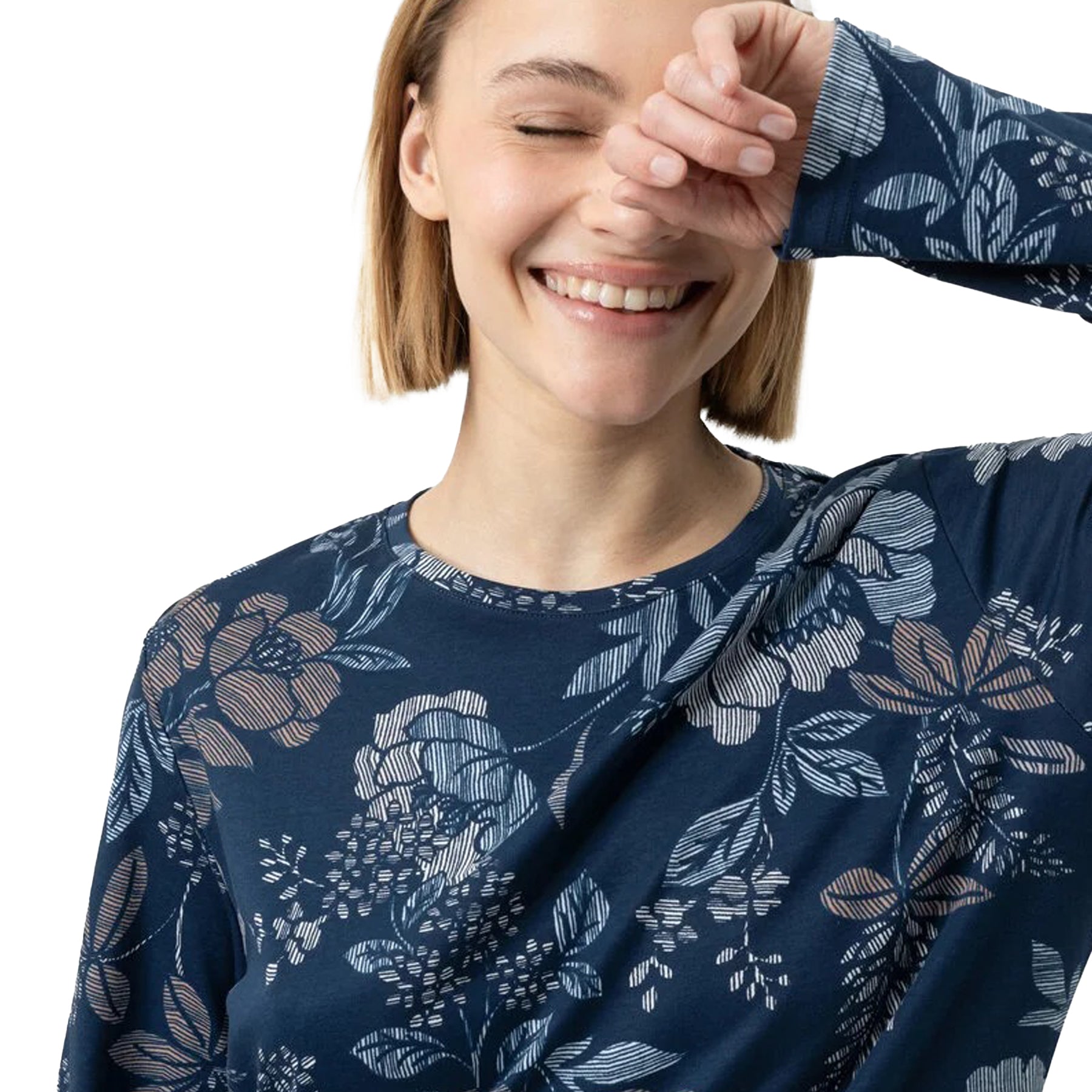 Close-up of woman smiling in a navy floral long-sleeve nightgown with soft pastel flower print.