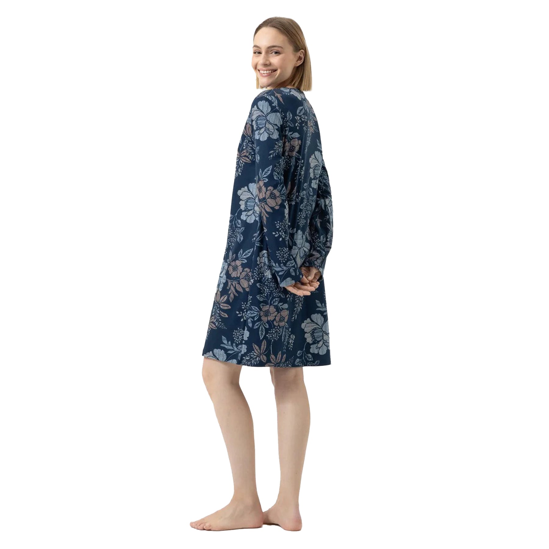 Woman turning and smiling in a navy floral nightgown with long sleeves and knee-length fit.