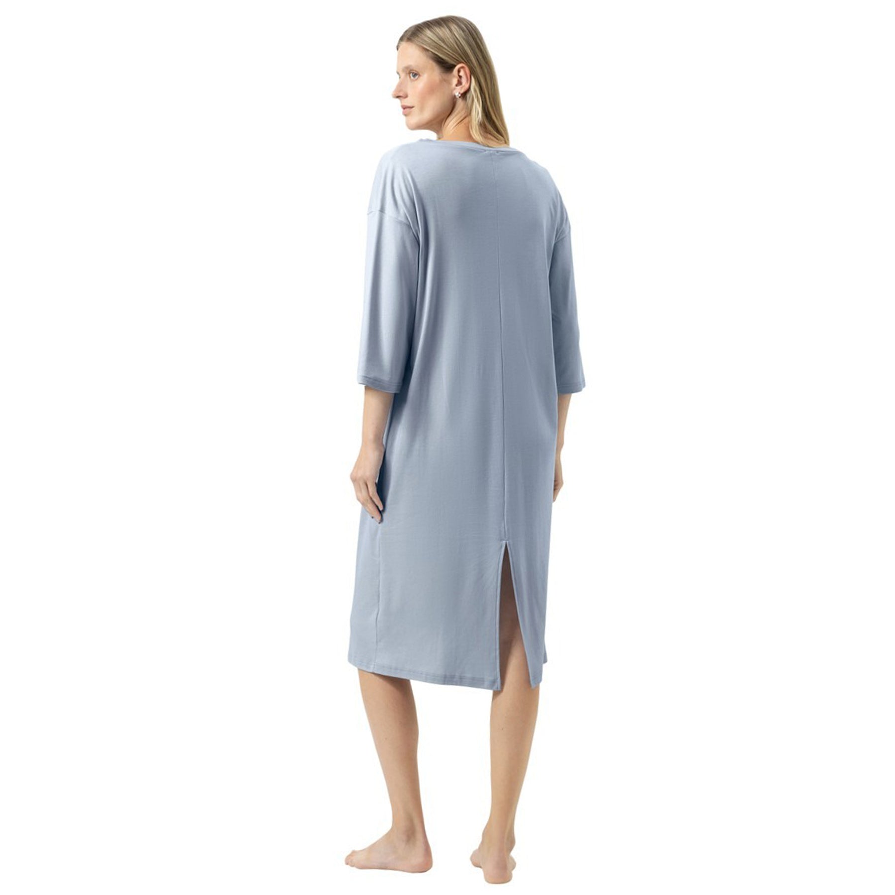 Back view of a woman wearing a relaxed knee-length nightdress in soft blue, featuring elbow-length sleeves and a small back slit at the hem.