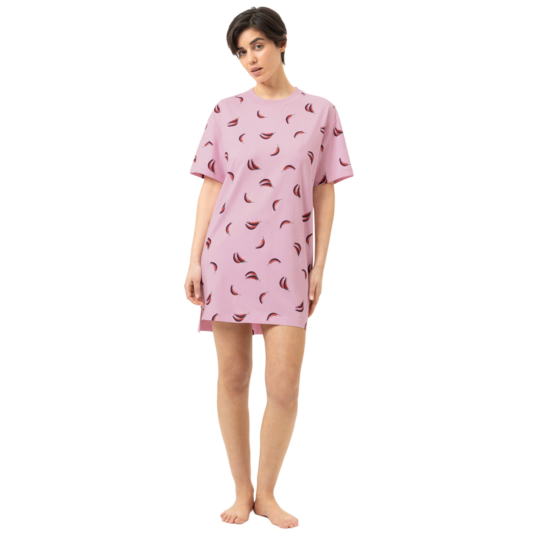 Front view of woman wearing a pink short-sleeve sleep shirt with an all-over red chili pepper print, crew neckline and relaxed fit.