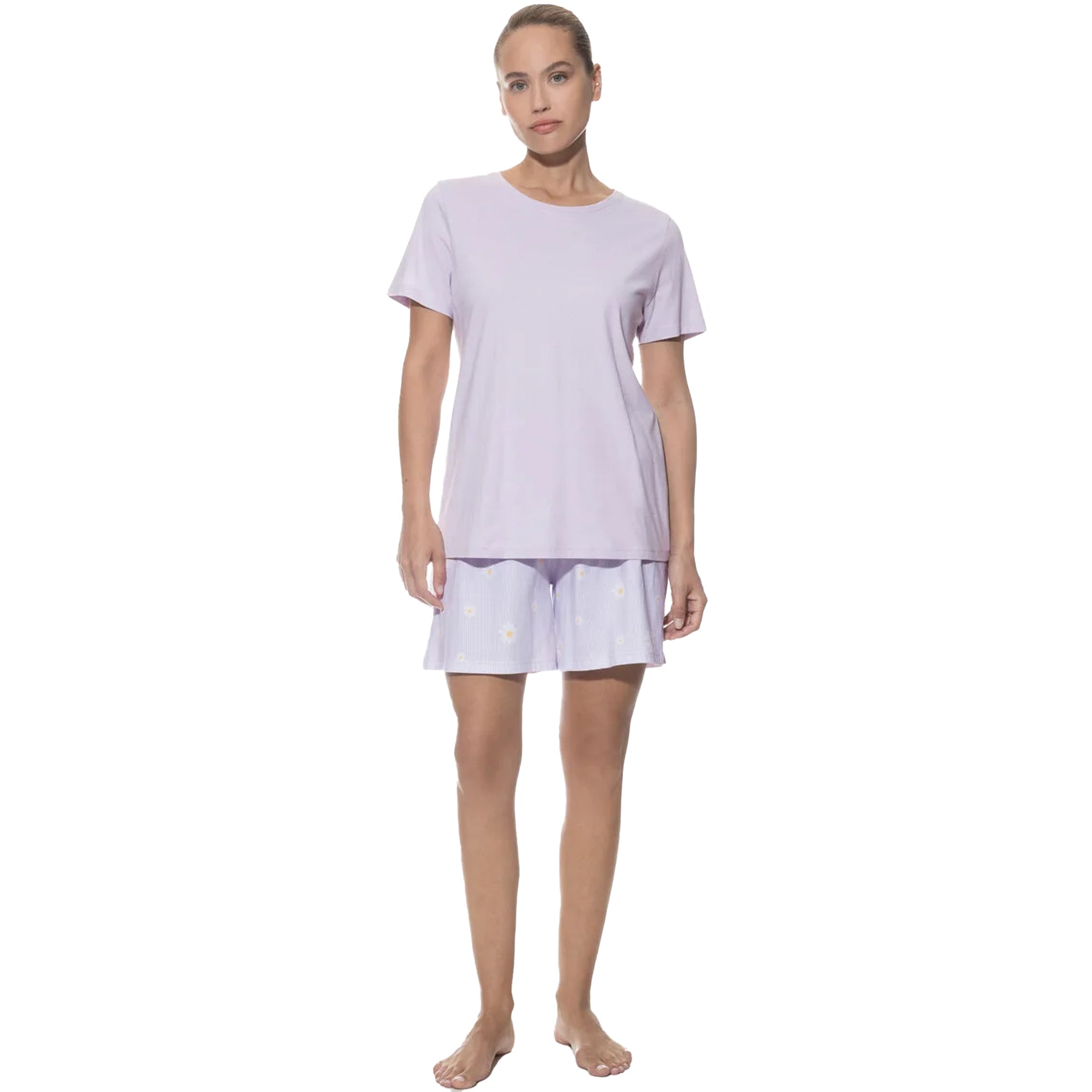 Woman wearing a lavender short-sleeve pajama set with a plain top and daisy-print shorts, standing facing forward.