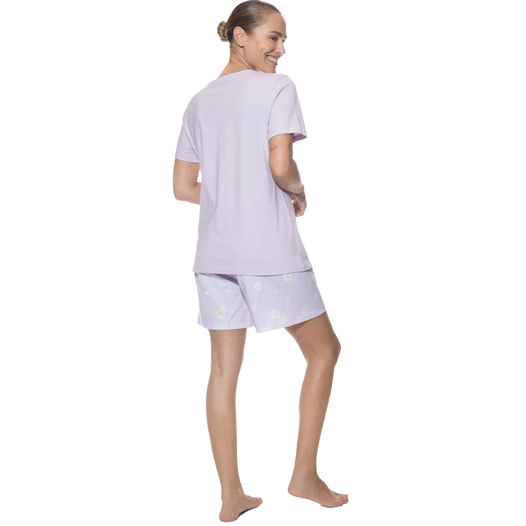 Woman showing the back of the lavender pajama set, smiling with hands by her side.