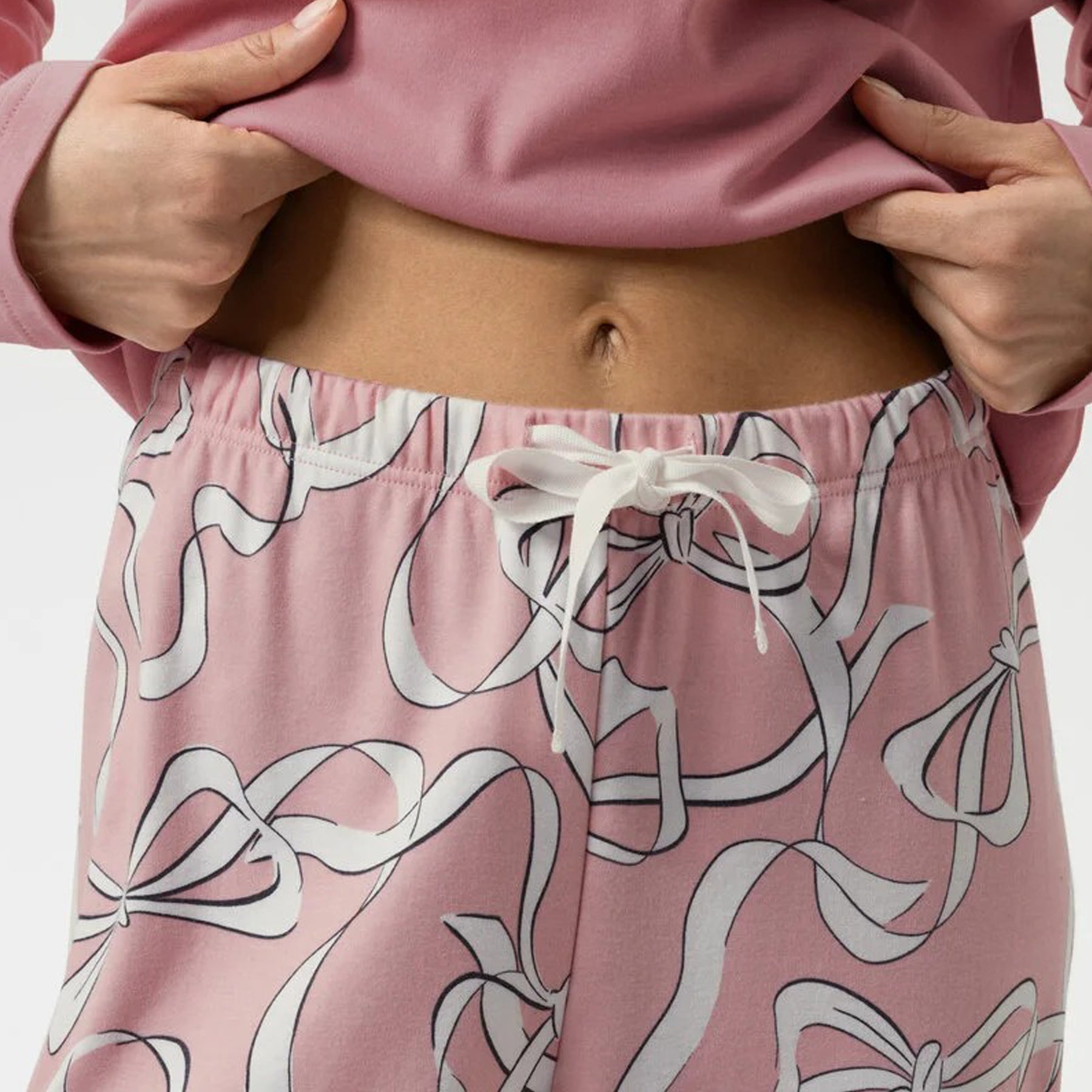 Close-up of drawstring waist on pink ribbon print pyjama pants.