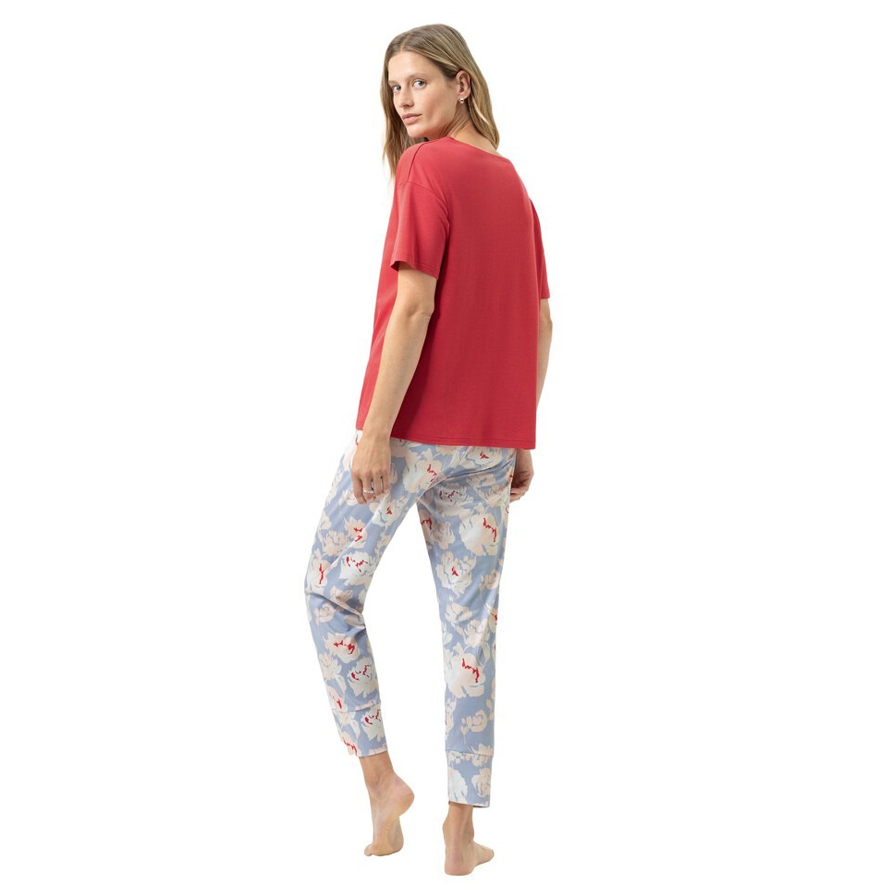 Back view of a woman wearing a red short-sleeve pyjama top with soft blue floral print pyjama pants, relaxed silhouette.
