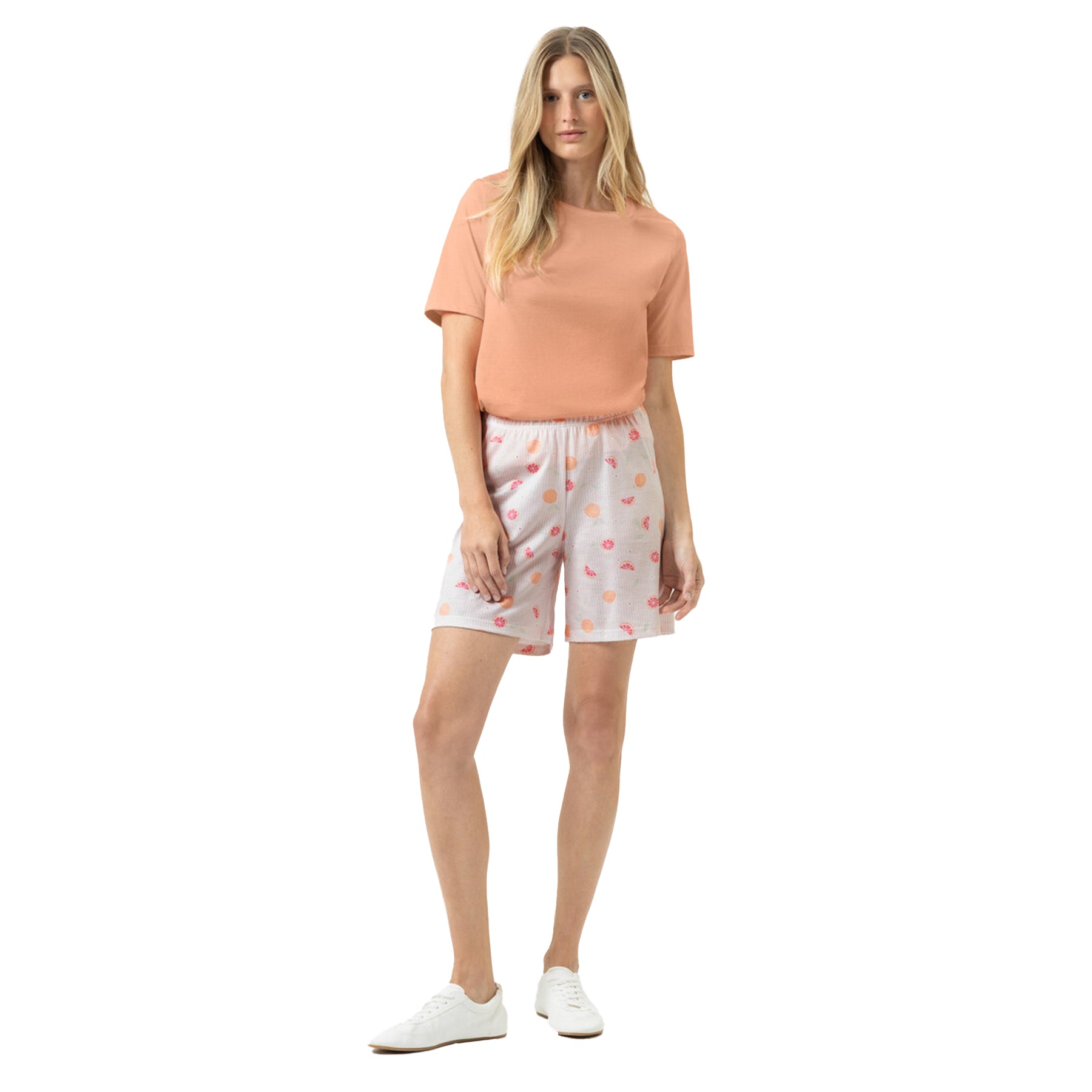 Woman wearing peach sleep T-shirt with citrus print lounge shorts styled casually with sneakers