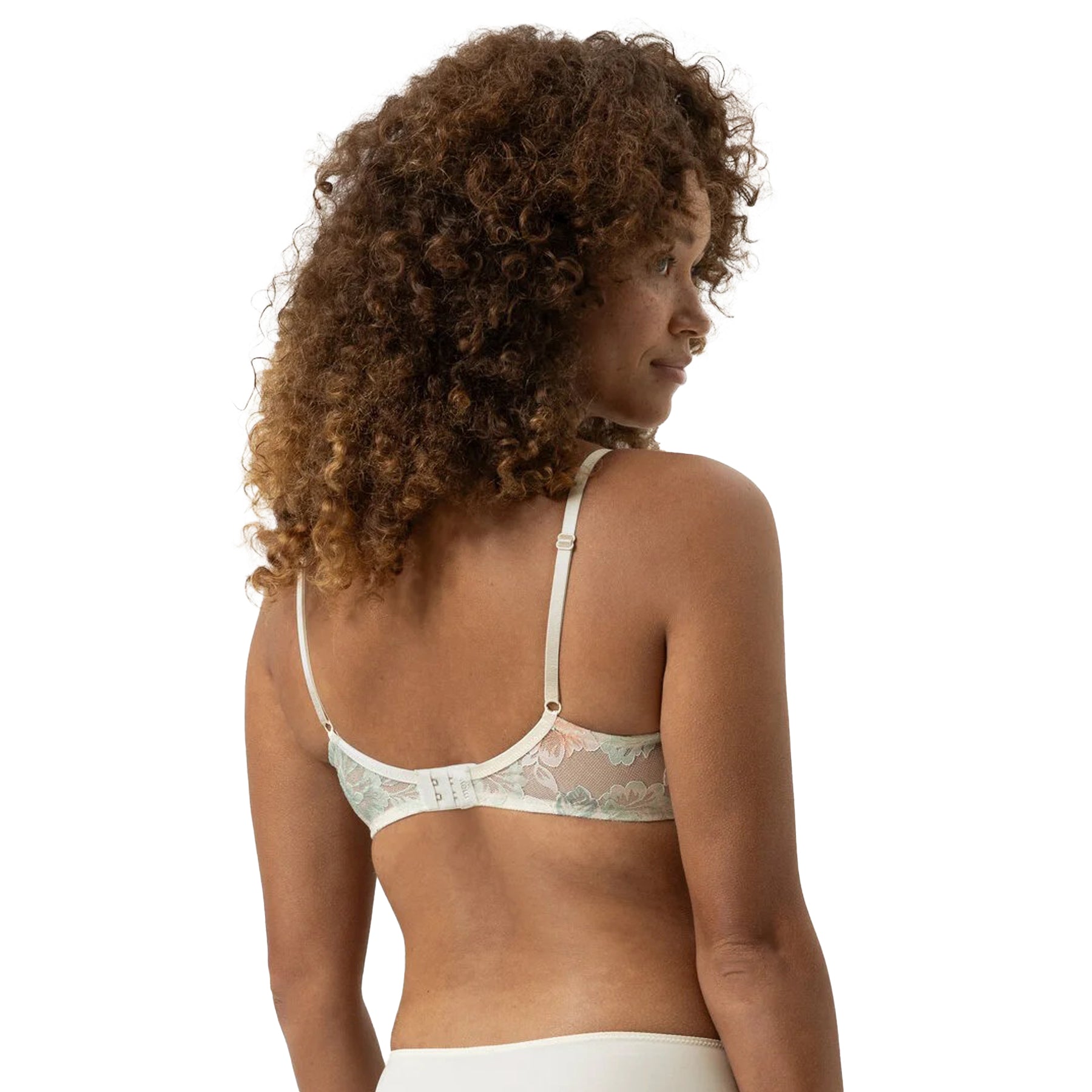 Woman wearing a light-colored lace bralette on a white background