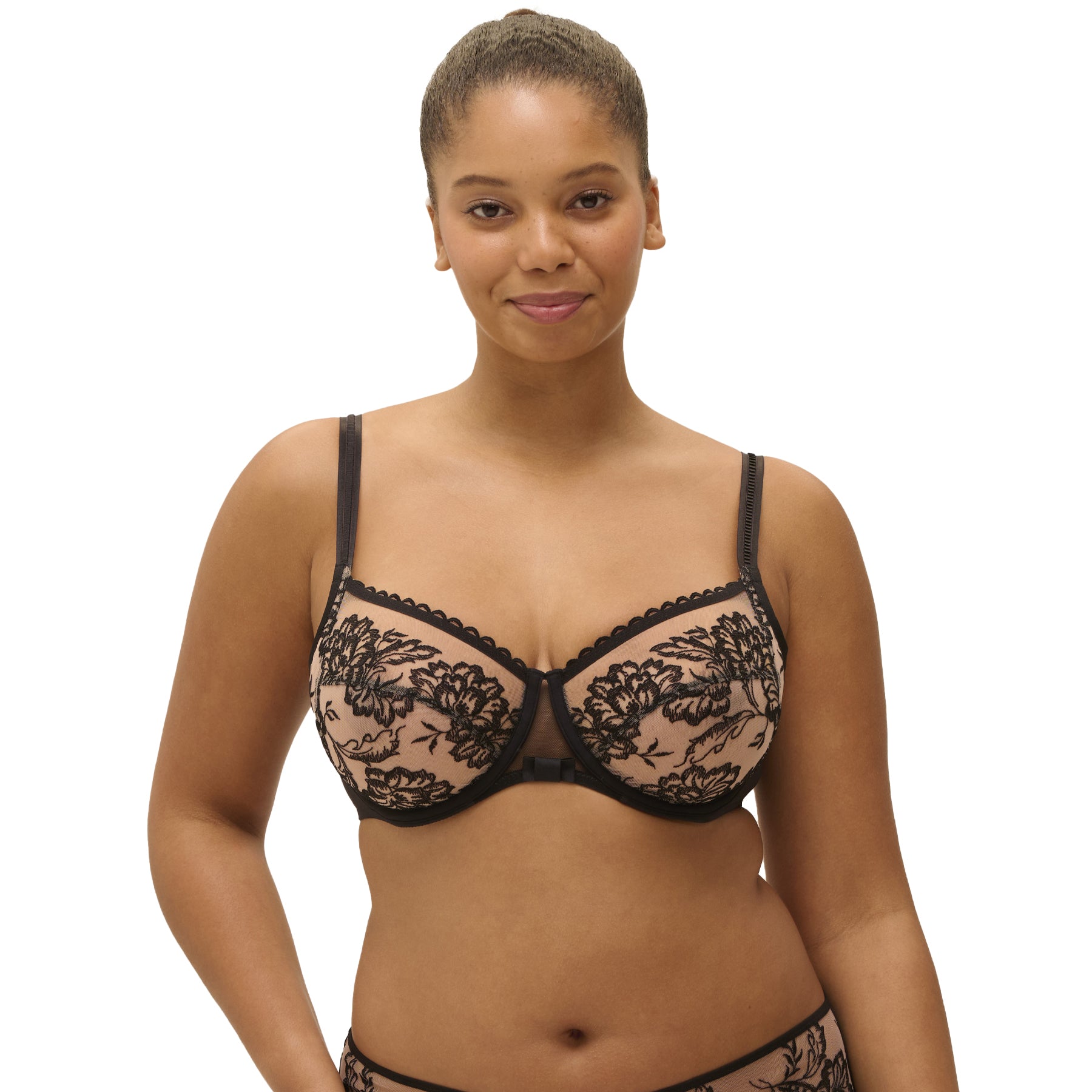 Woman wearing black floral embroidered full cup bra with sheer mesh and scalloped trim, front facing.