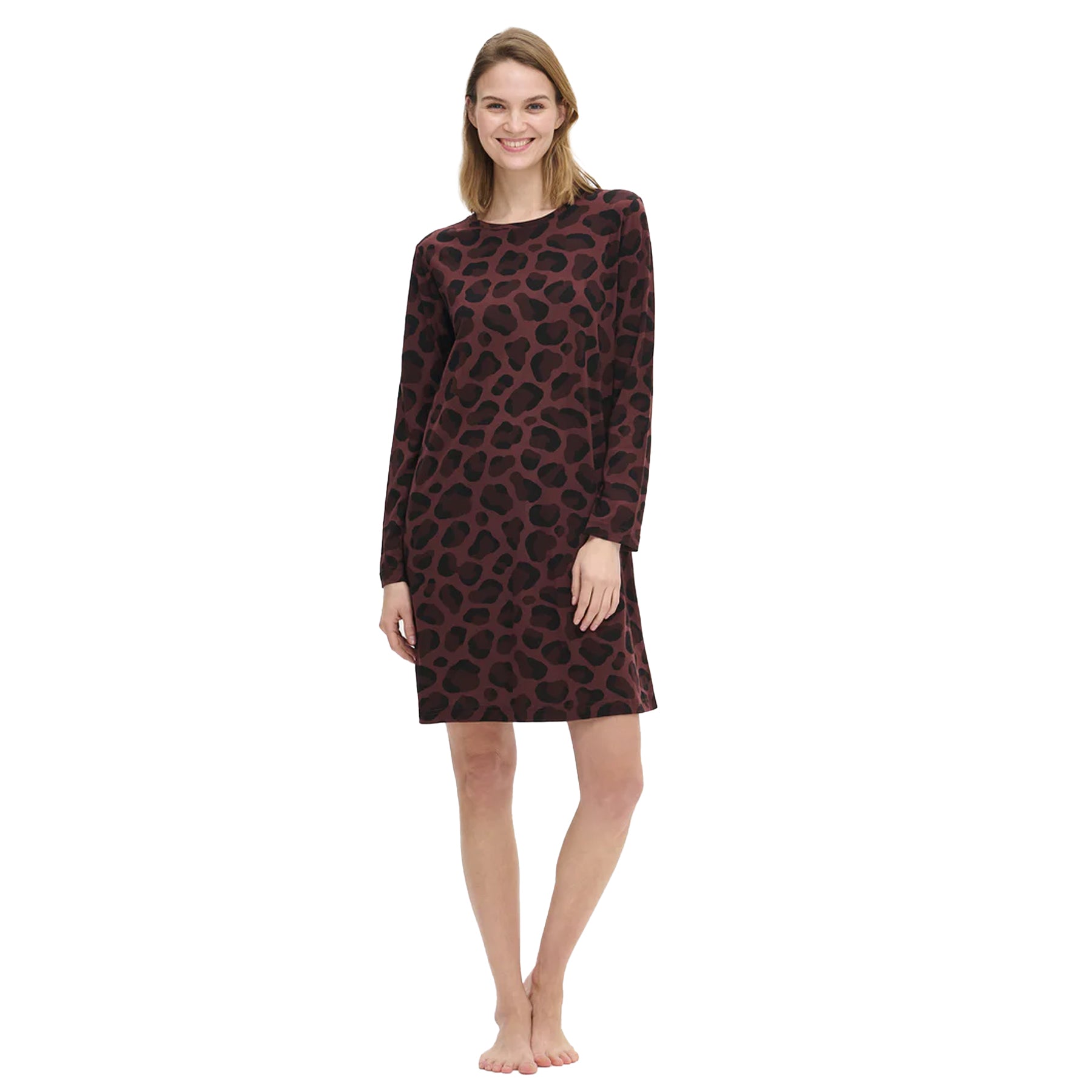 Woman wearing a long-sleeve burgundy chemise with a black leopard print, standing barefoot and smiling against a white background.