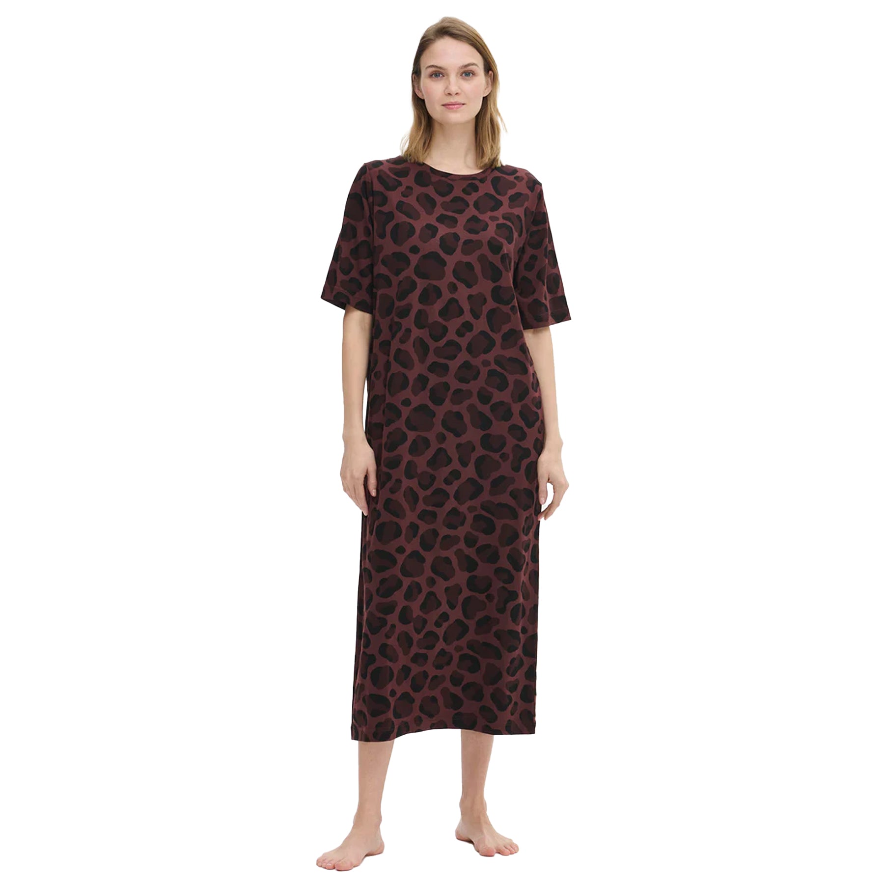 Woman wearing a long burgundy nightdress with a black leopard print, short sleeves, and relaxed fit, standing barefoot against a white background.