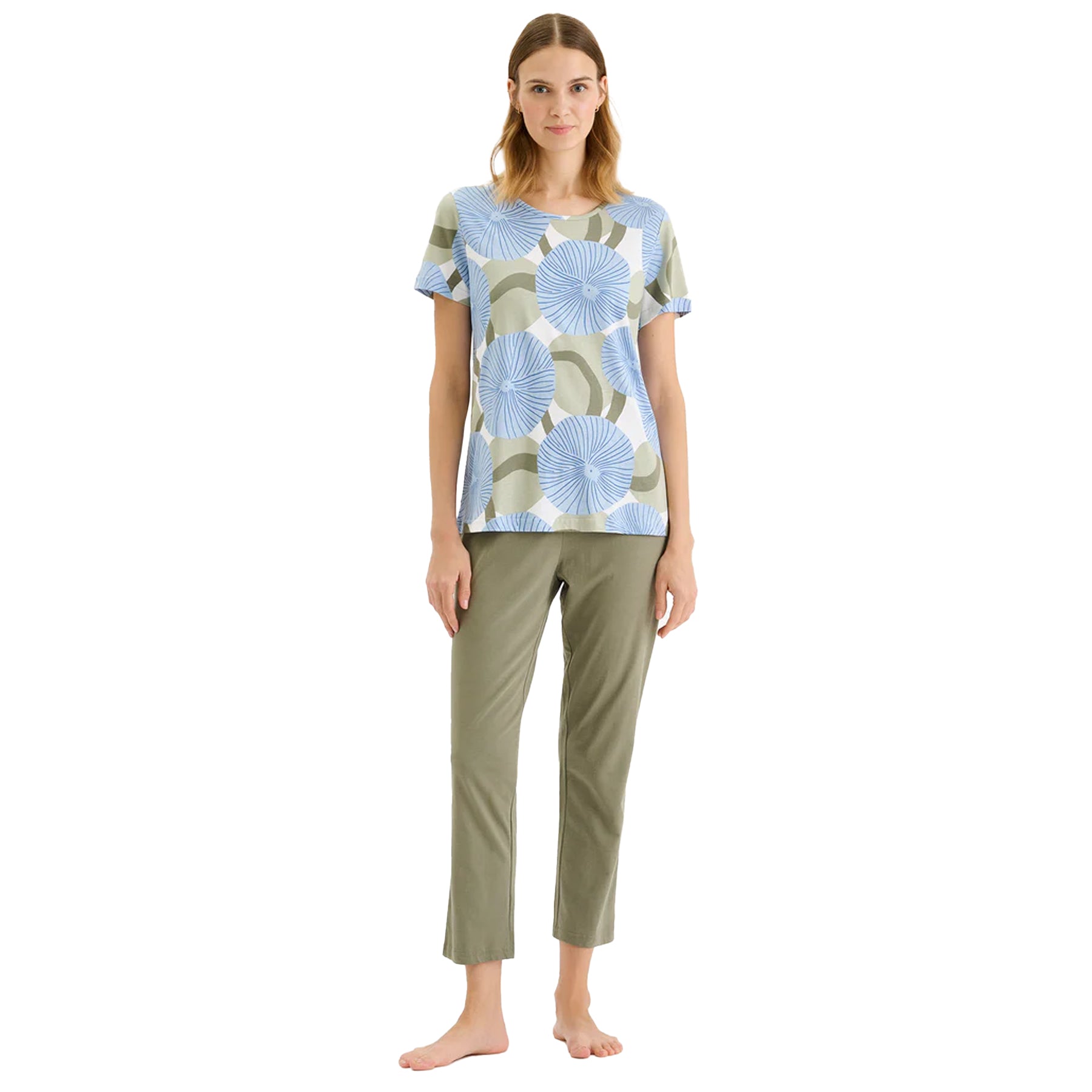 Woman wearing a blue and sage green circular floral print short-sleeve pajama top with solid sage green pants.