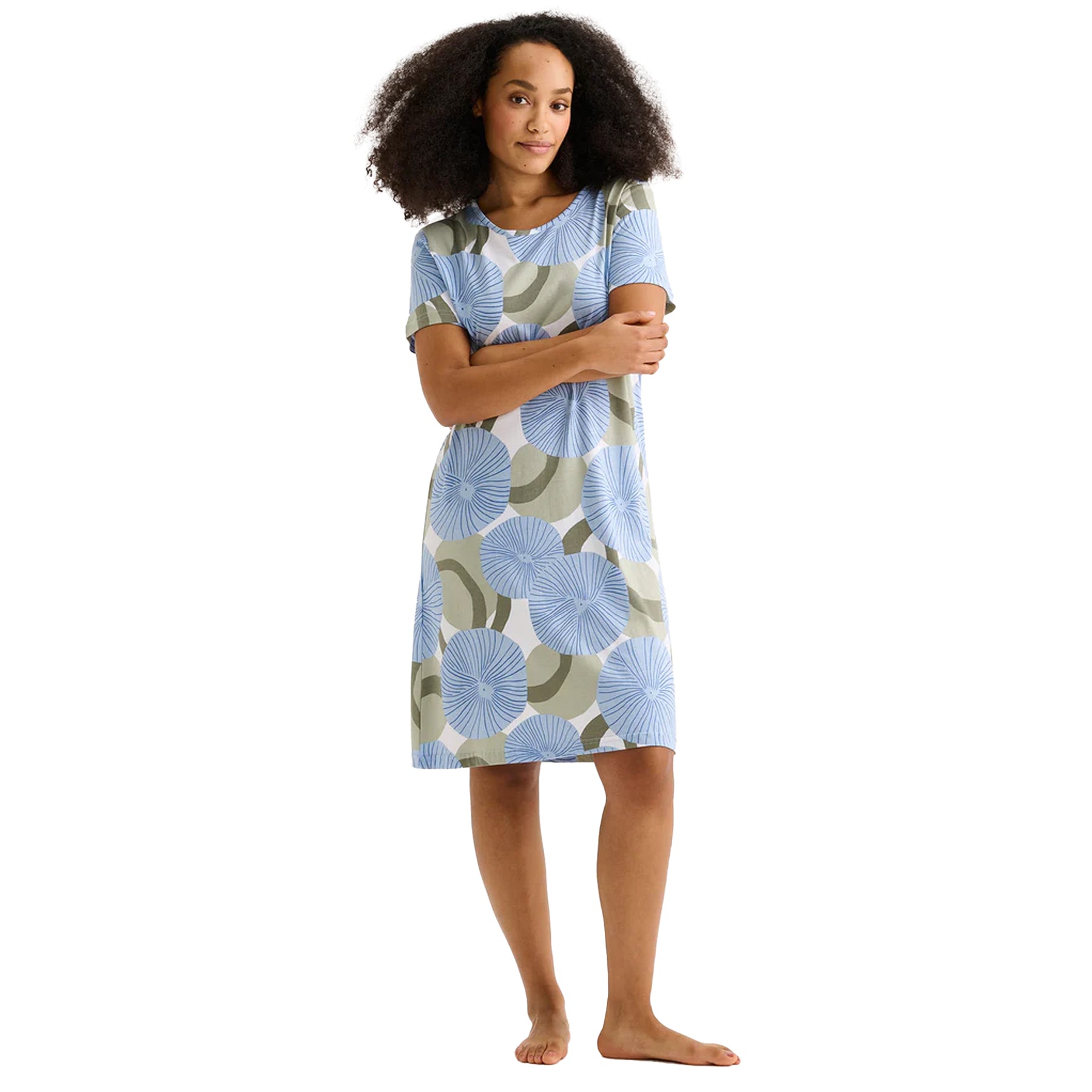 Woman wearing a blue circular floral print short-sleeve chemise nightdress with relaxed knee-length fit.