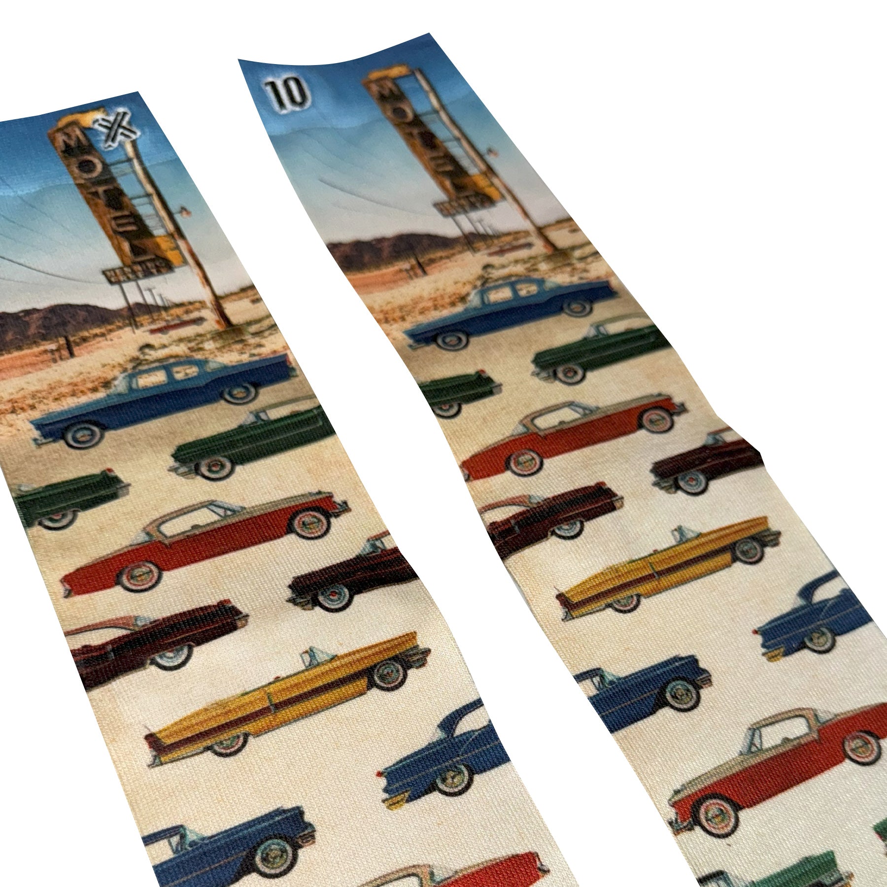 Close-up of car print socks highlighting colourful vintage vehicles against a desert motel backdrop.