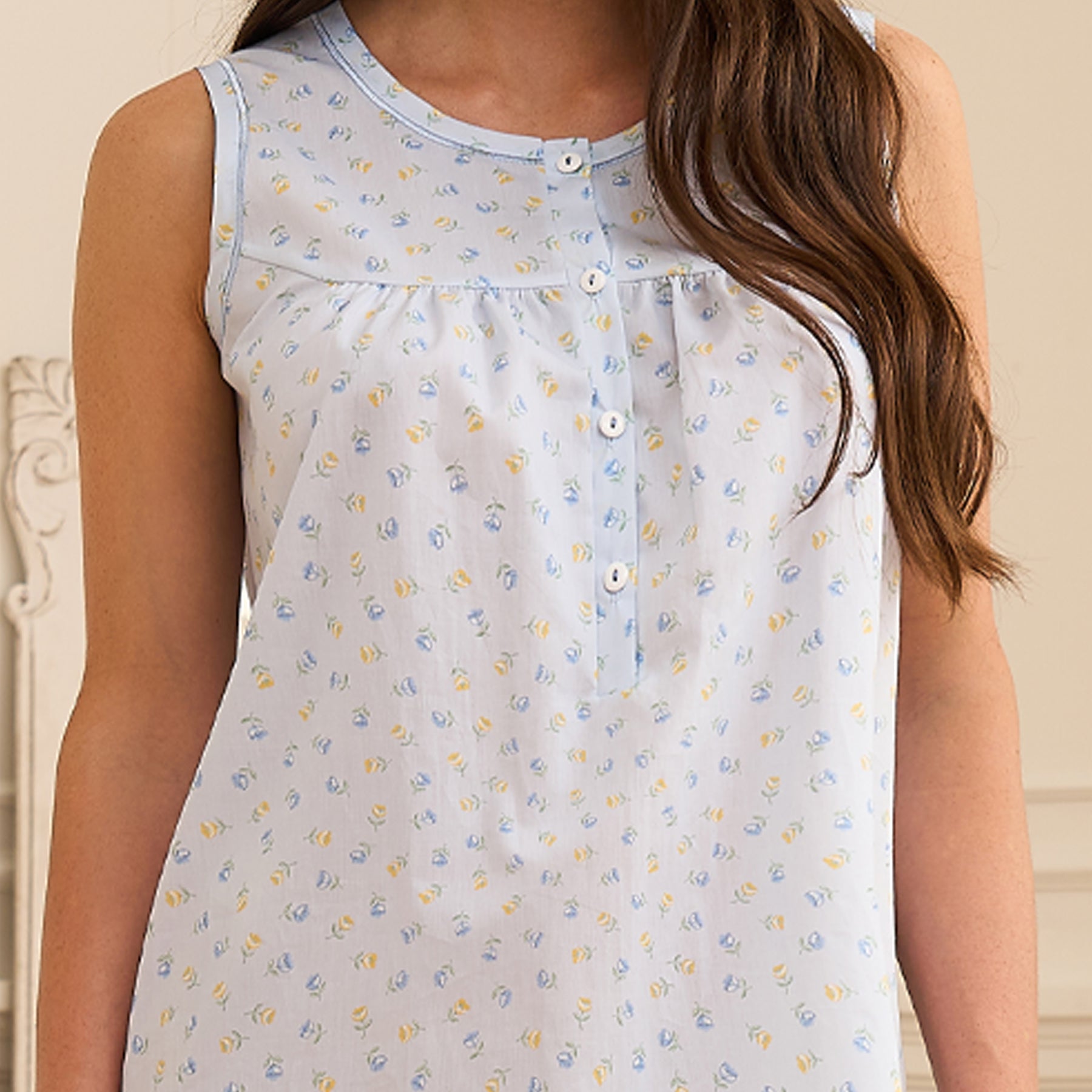 Close-up of light blue floral cotton nightgown featuring delicate mini print, round neckline, button placket, and softly gathered front yoke