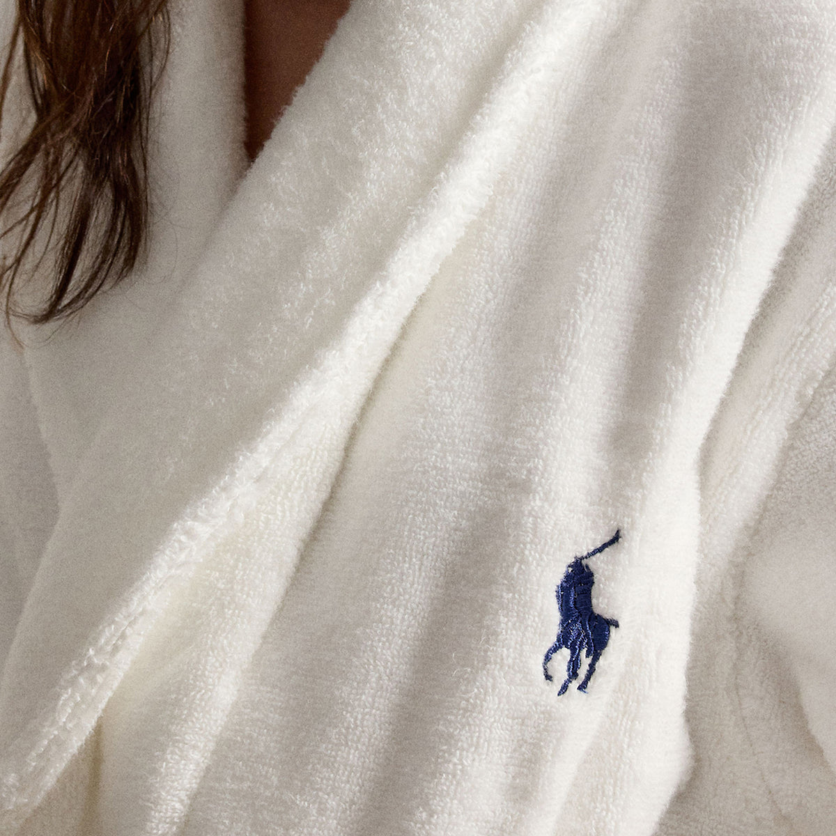 Close-up of Polo Ralph Lauren white plush fleece robe highlighting the soft, fluffy texture, shawl collar, and signature navy embroidered Polo Pony logo.
