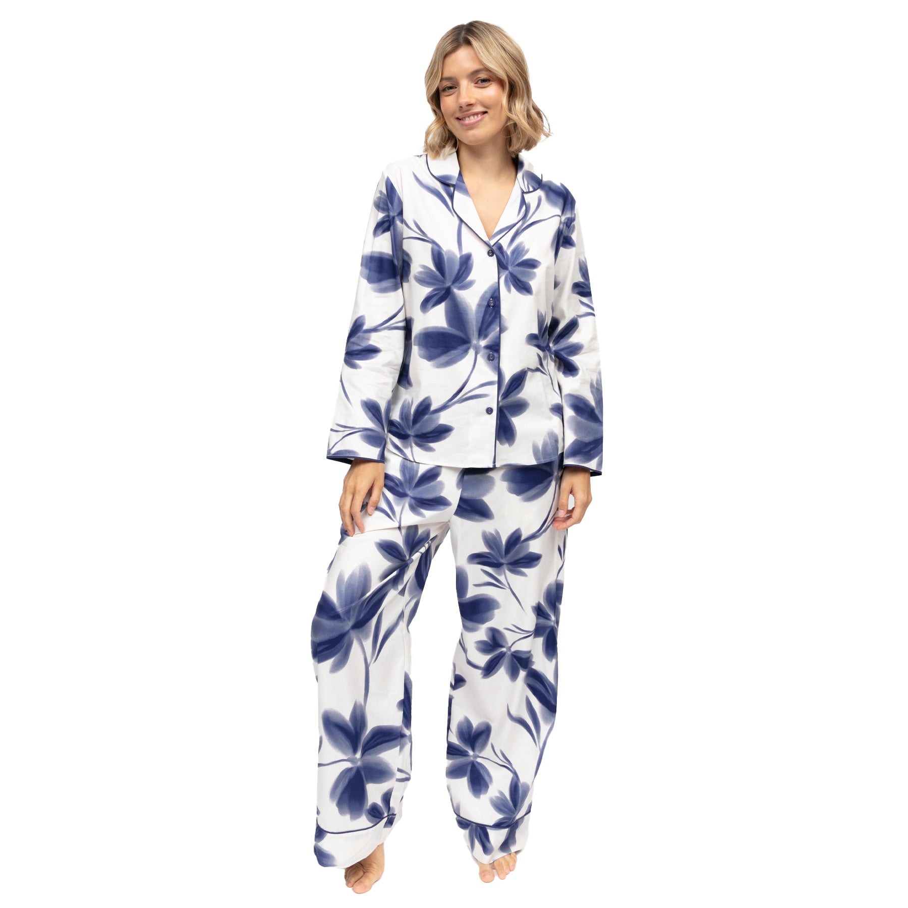 Model wearing navy floral print pyjama set featuring a collared button-front top and relaxed fit full-length pants.