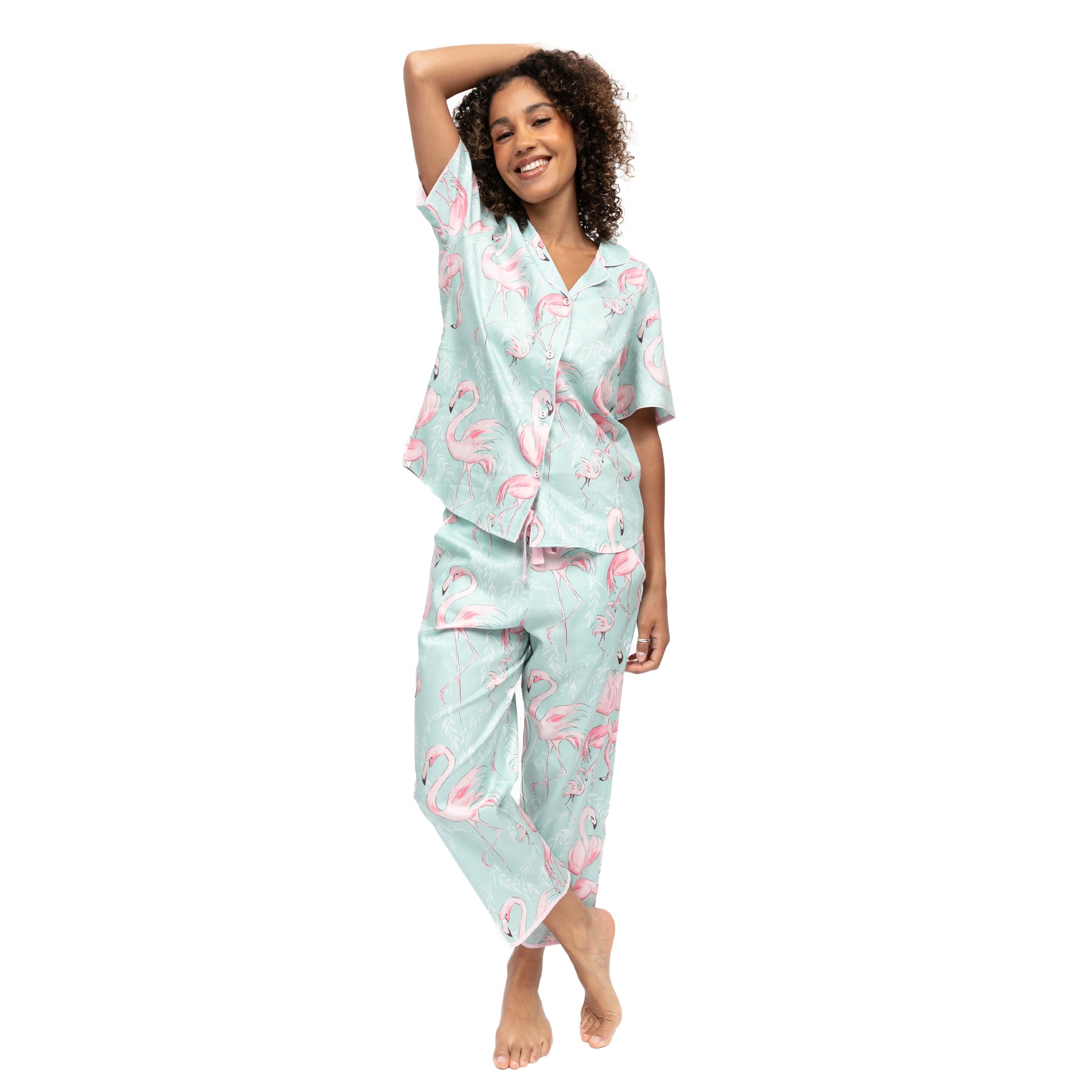 Woman posing in mint flamingo print pyjamas with button-front top and cropped pants, playful tropical sleepwear