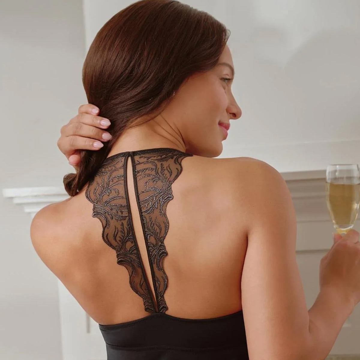Model wearing the black Fleur Racerback Chemise, highlighting the sheer floral lace racerback design, lifestyle back view.