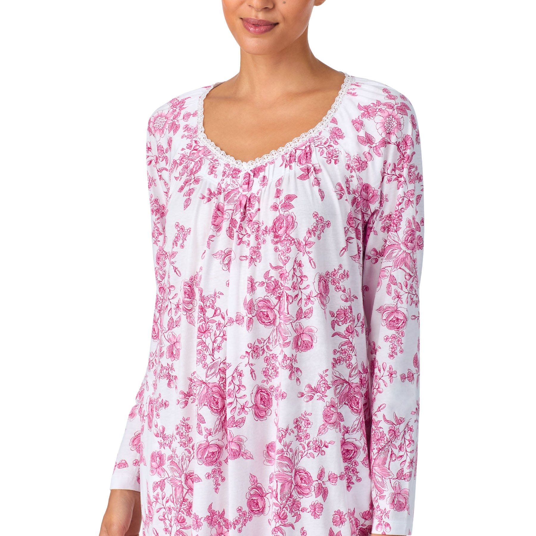 Woman wearing a white long-sleeve top with pink floral pattern on a white background