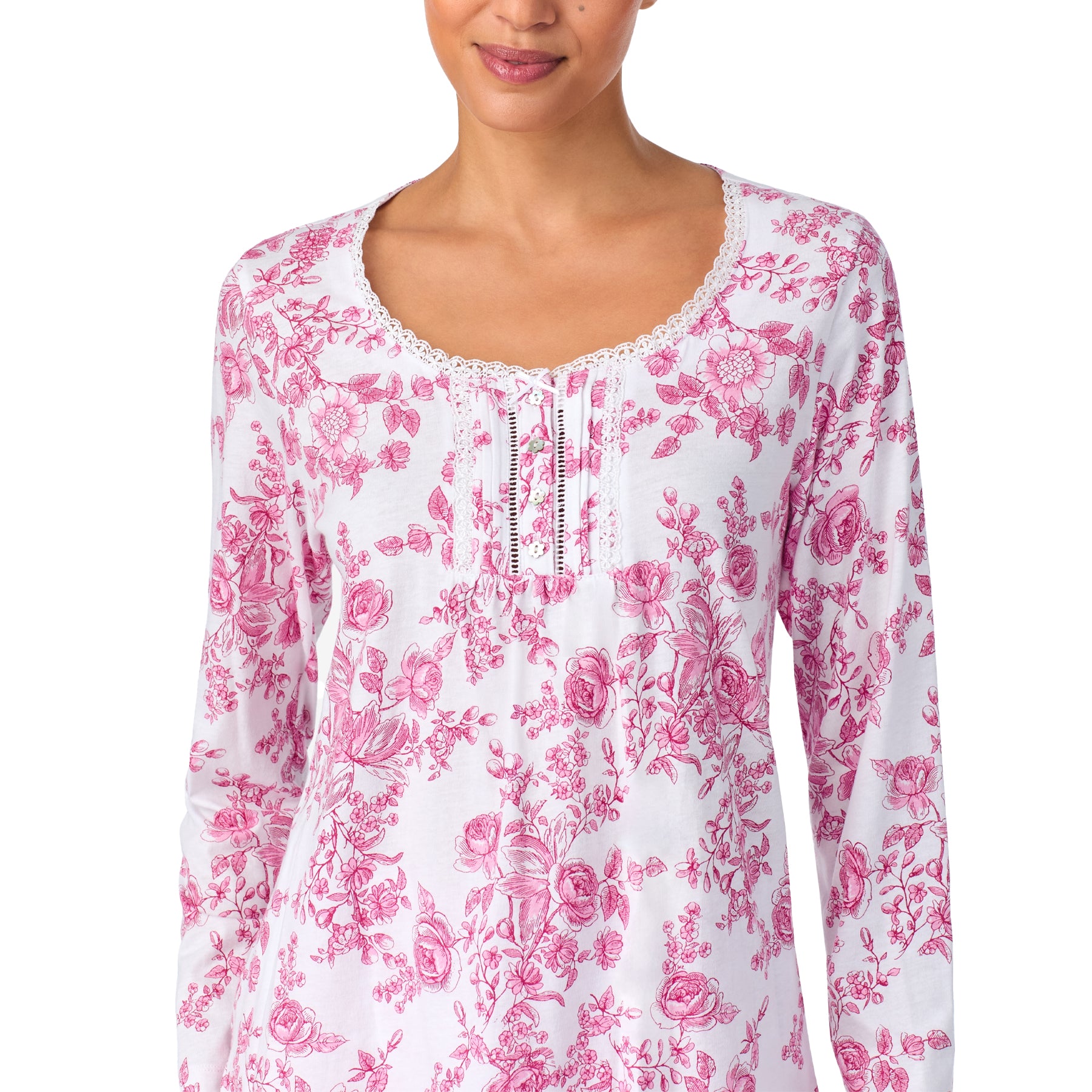 Woman wearing a white long-sleeve top with pink floral pattern on a white background