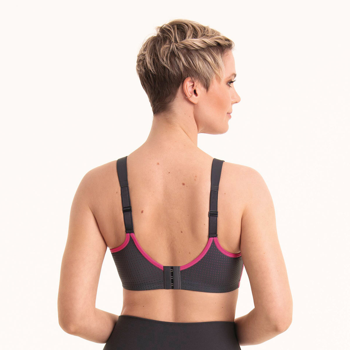 Anita 5599 performance wireX sports bra in 481 anthrazit/pink; a charcoal grey with hot pink trim. Rear view on model.