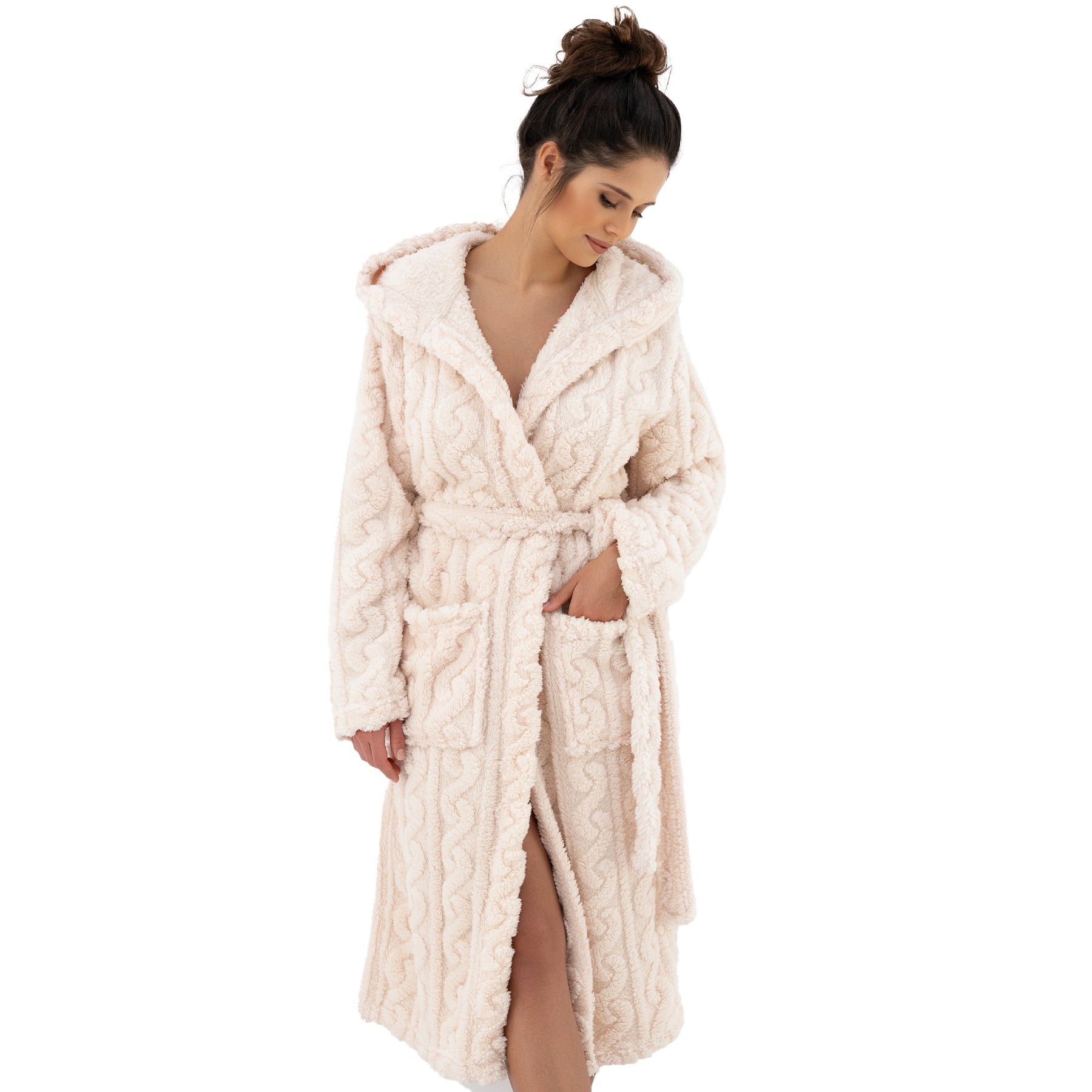 Woman wearing hooded cream robe with waist belt and relaxed fit, looking down with hands in pockets.