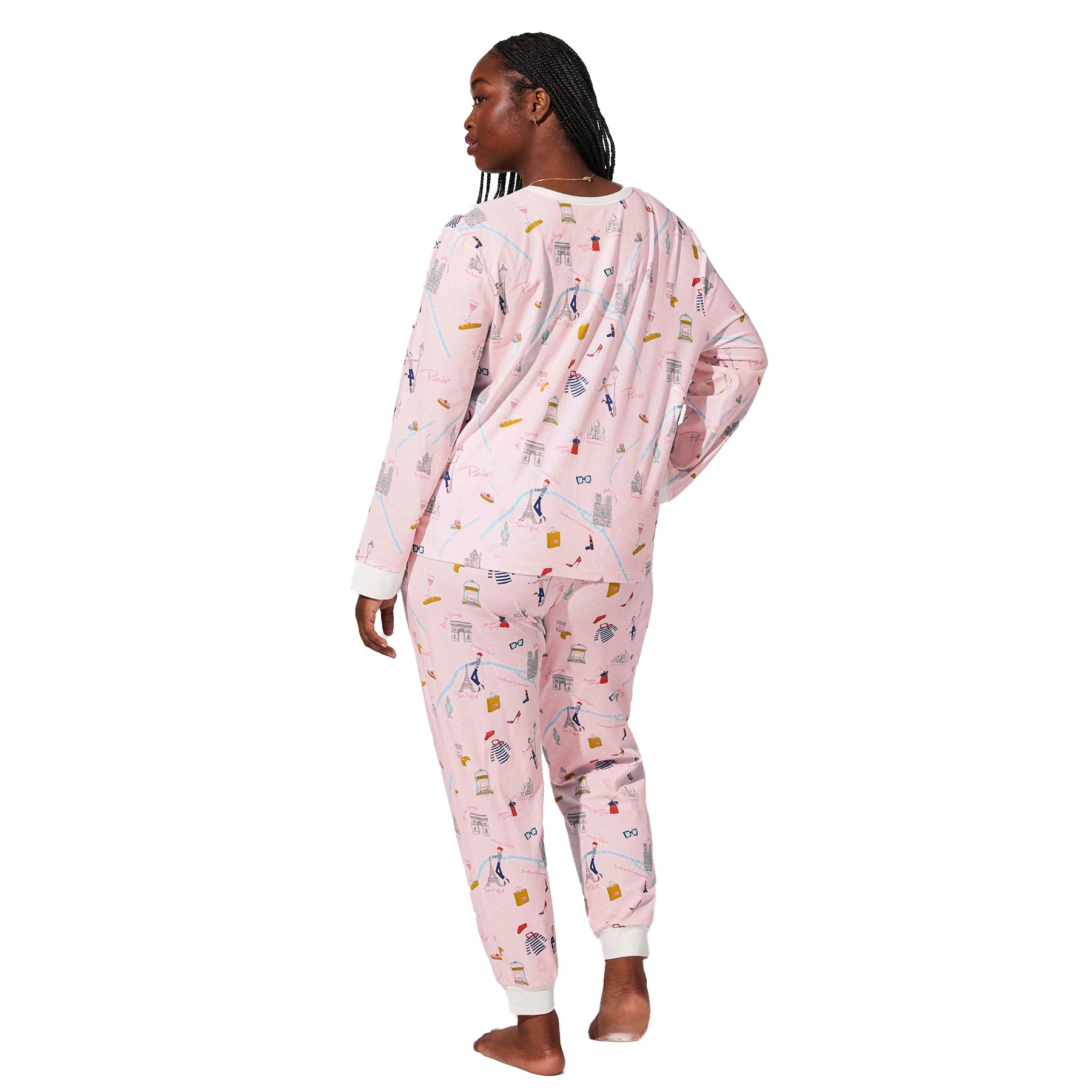 Back angled view of plus-size model wearing pink Paris-themed pajama set with multicolour illustrated print.