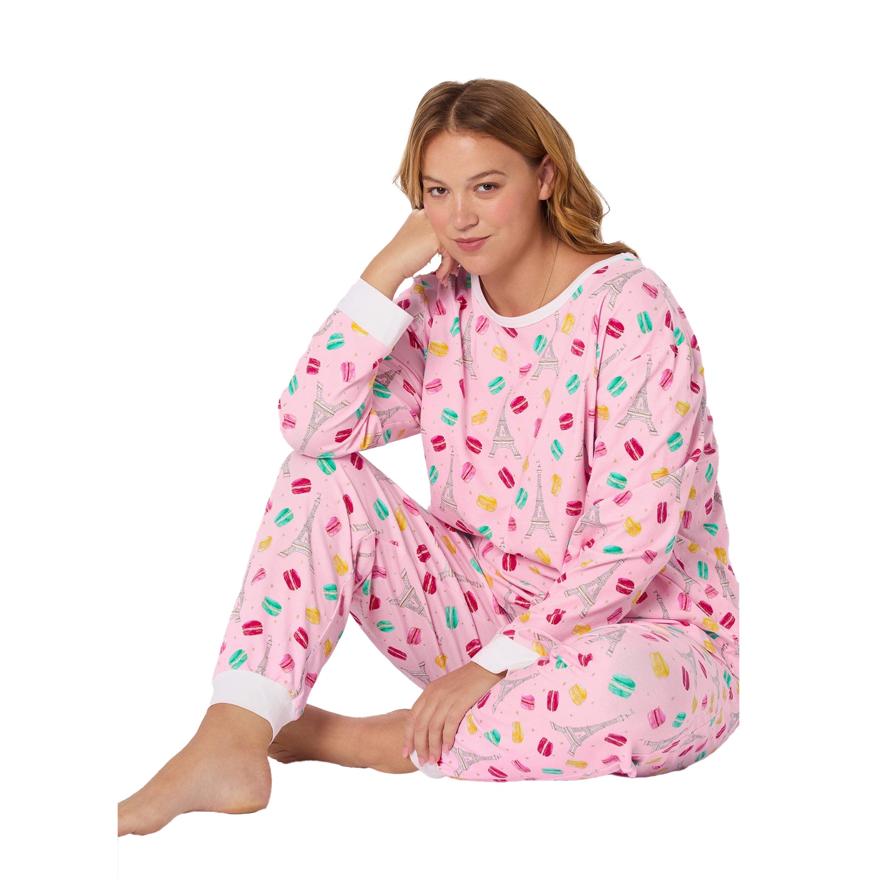 Woman wearing a pink pajama set with colorful patterns on a white background