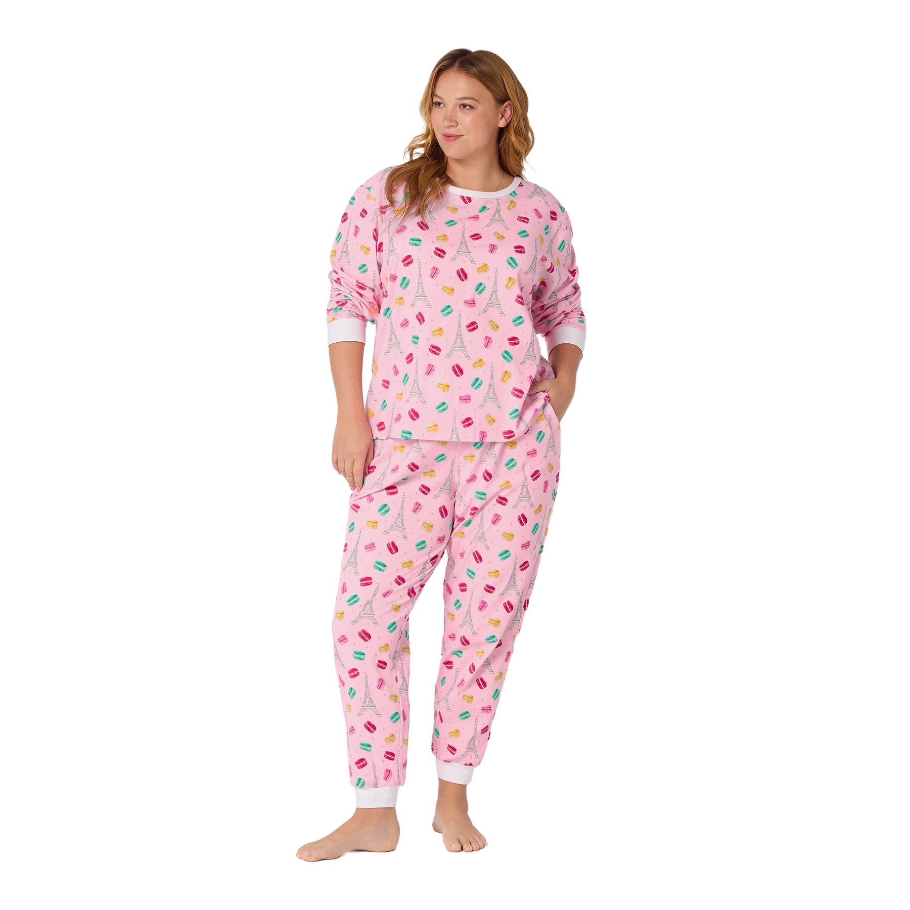 Woman wearing a pink pajama set with colorful patterns on a white background