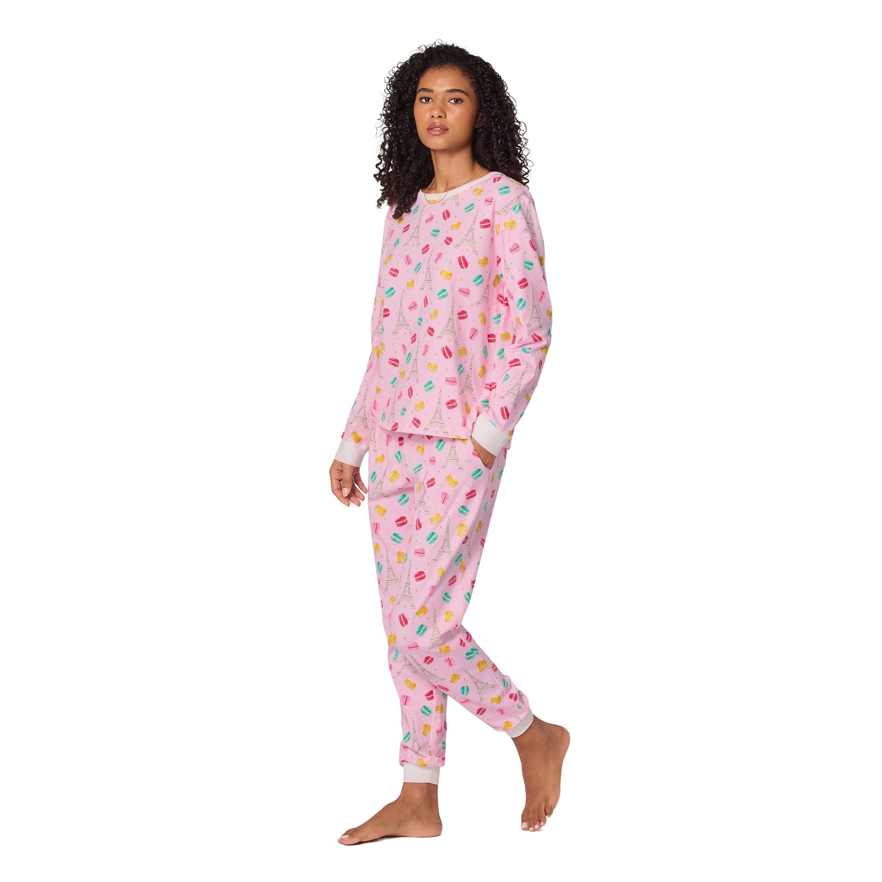 Woman wearing a pink pajama set with colorful patterns on a white background