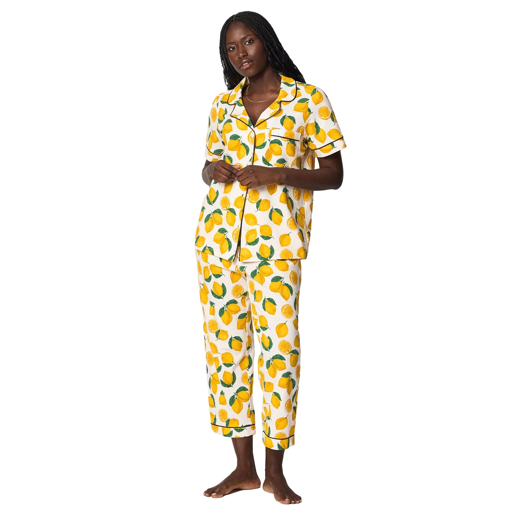 Woman wearing white cotton pyjama set with vibrant yellow lemon print and relaxed comfortable fit.