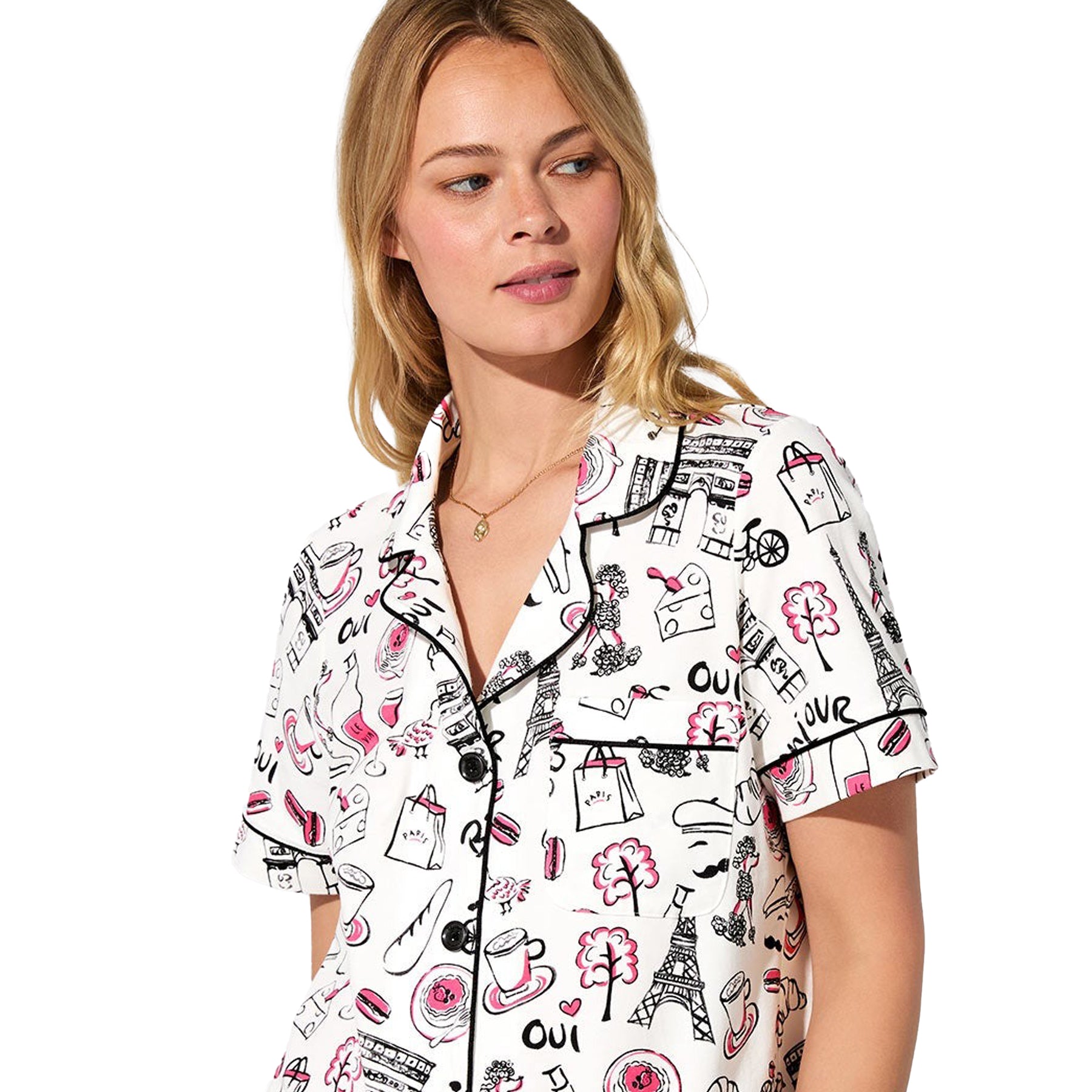 Close-up of straight-size model wearing Paris print pajama top with black piping and whimsical French-themed illustrations.