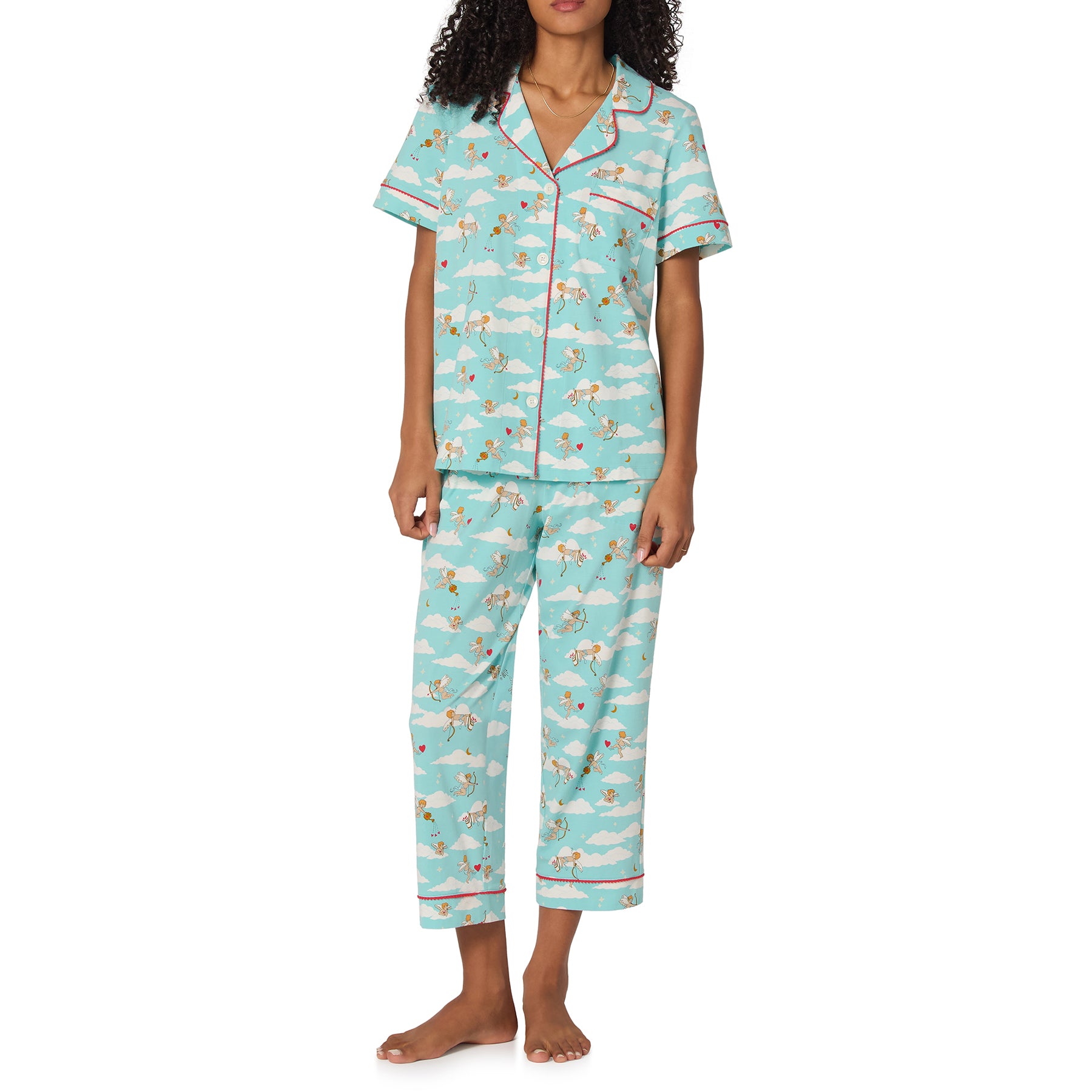 Woman wearing a blue pajama set with cloud and sheep pattern on a white background