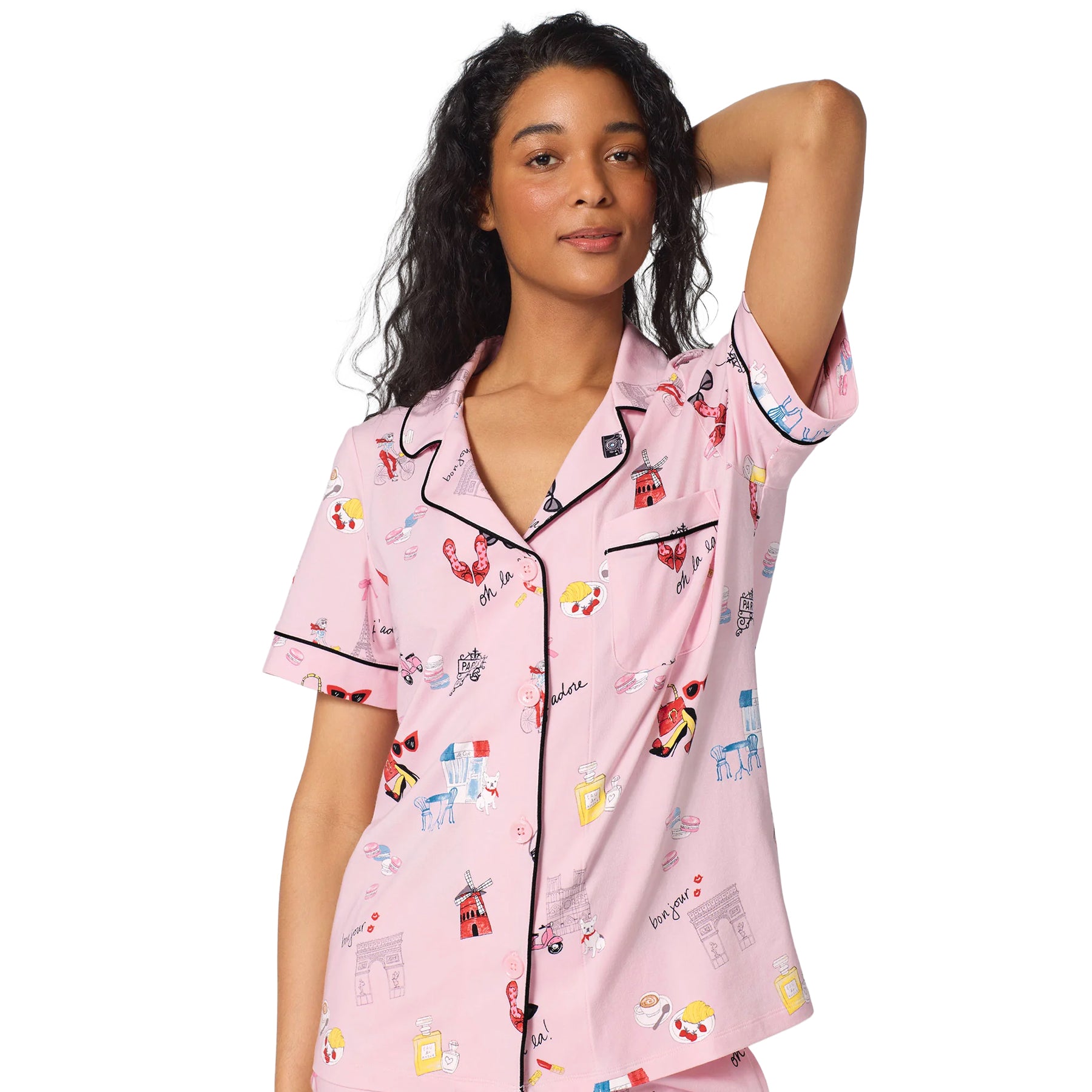 Close-up of a pink pajama top featuring a playful Paris print, notched collar, chest pocket, button front and black piping.