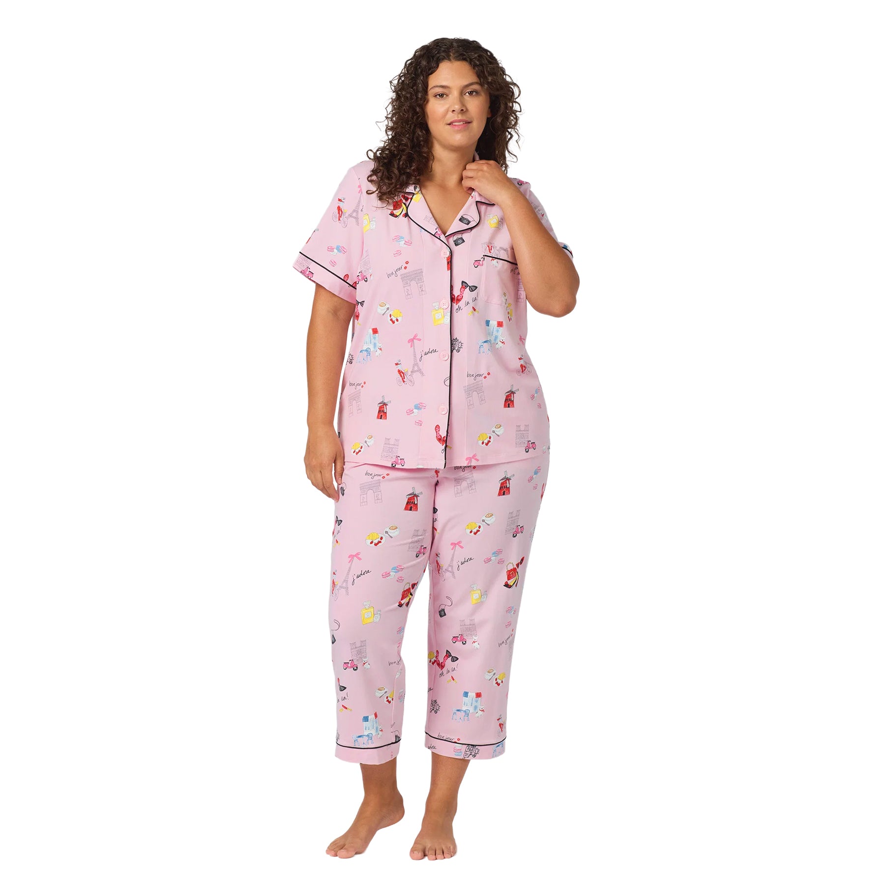 Plus-size woman wearing a pink short-sleeve pajama set with cropped pants, Paris-inspired print and black contrast piping.