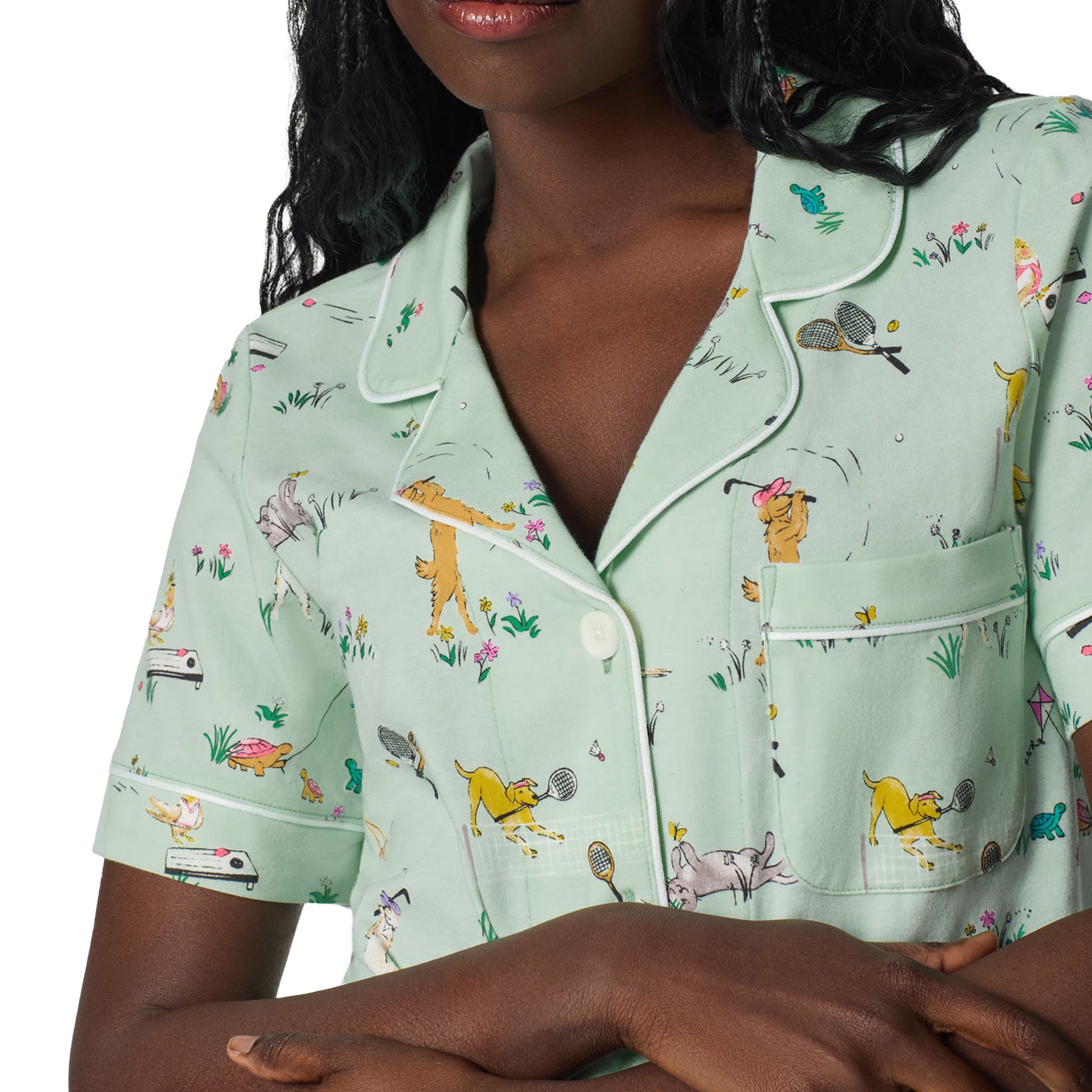 Close-up detail of mint green pajama shirt with white piping, chest pocket and whimsical dog and tennis print pattern.