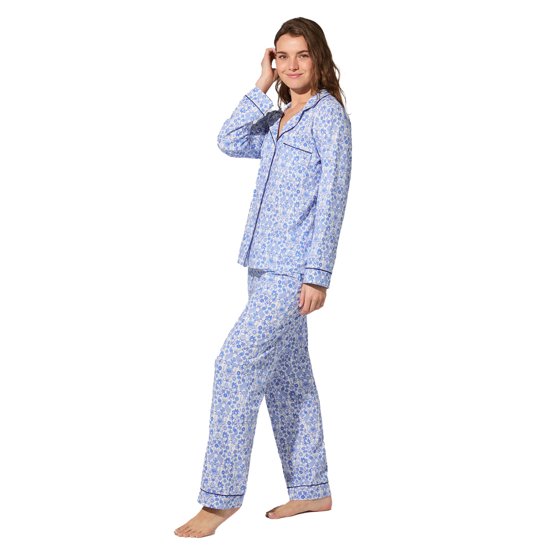 Side view of woman wearing white and blue floral pyjama set with navy piping detail.