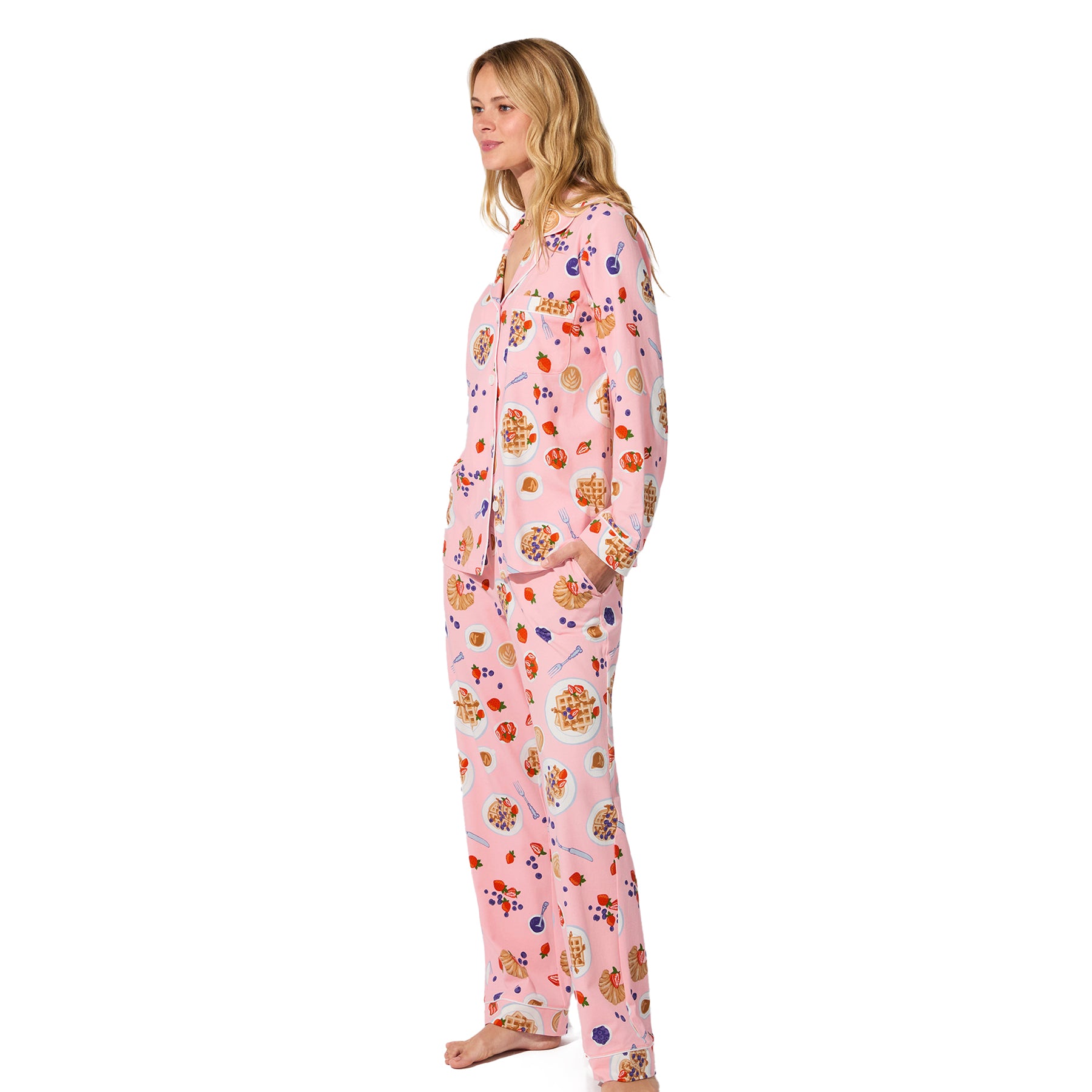 Woman wearing pink waffle brunch print pyjama set, side view with pockets.