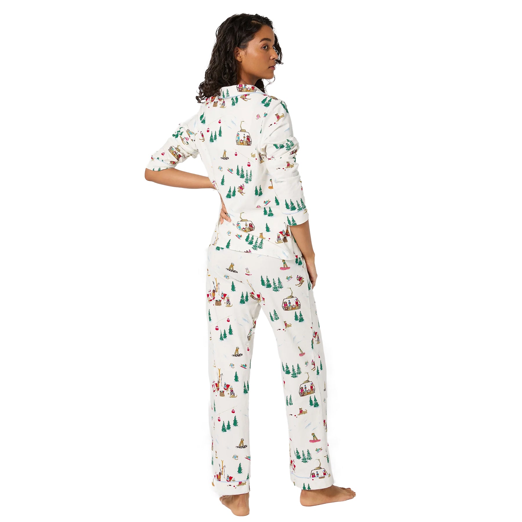 Back view of white ski-print cotton pyjama set featuring winter scene pattern with trees and dogs.