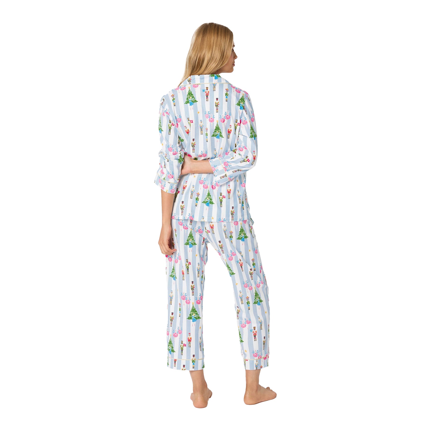 Woman wearing a colorful pajama set with a pattern of trees and people on a white background