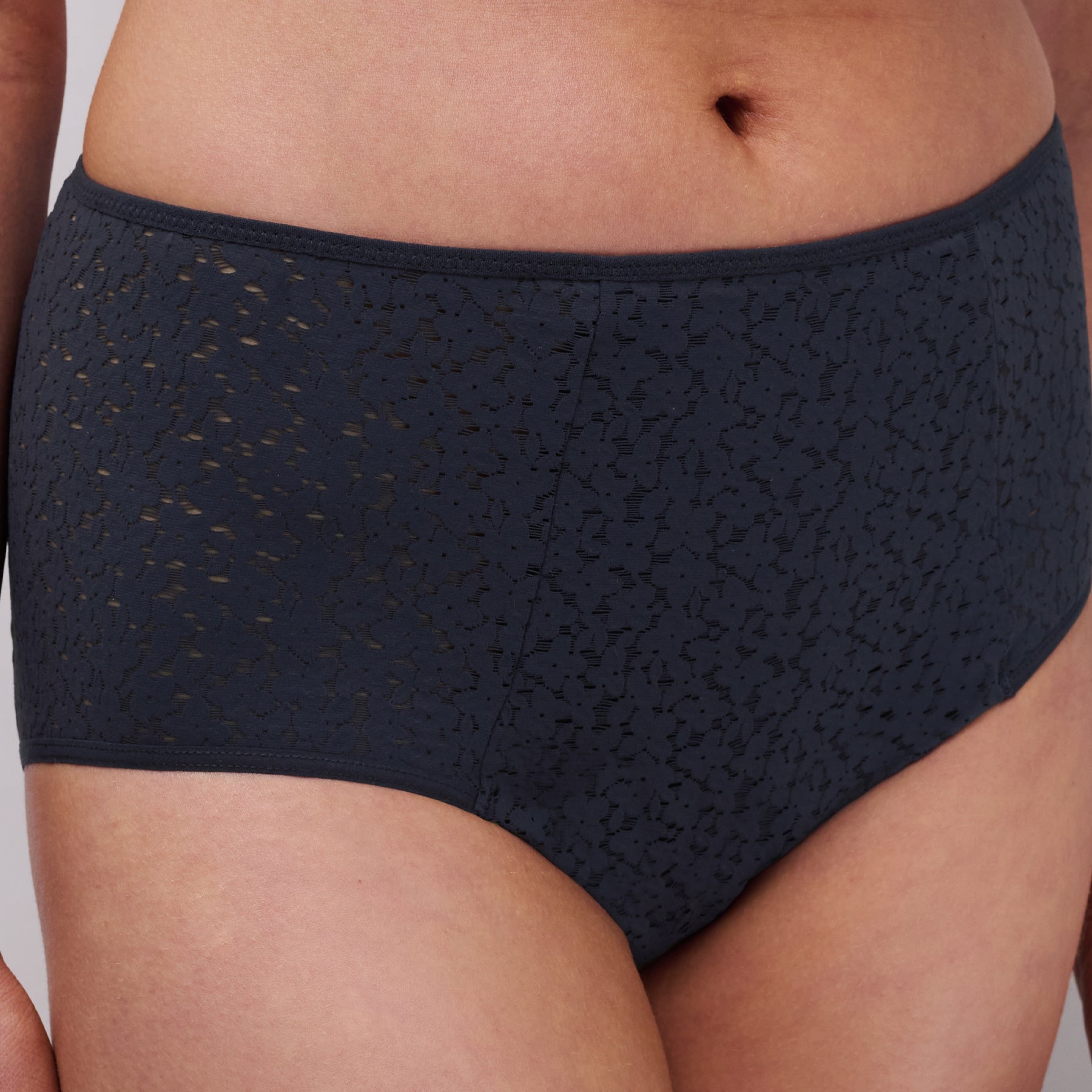 Close-up side view of navy high-waisted brief highlighting semi-sheer lace texture and flattering waistband.